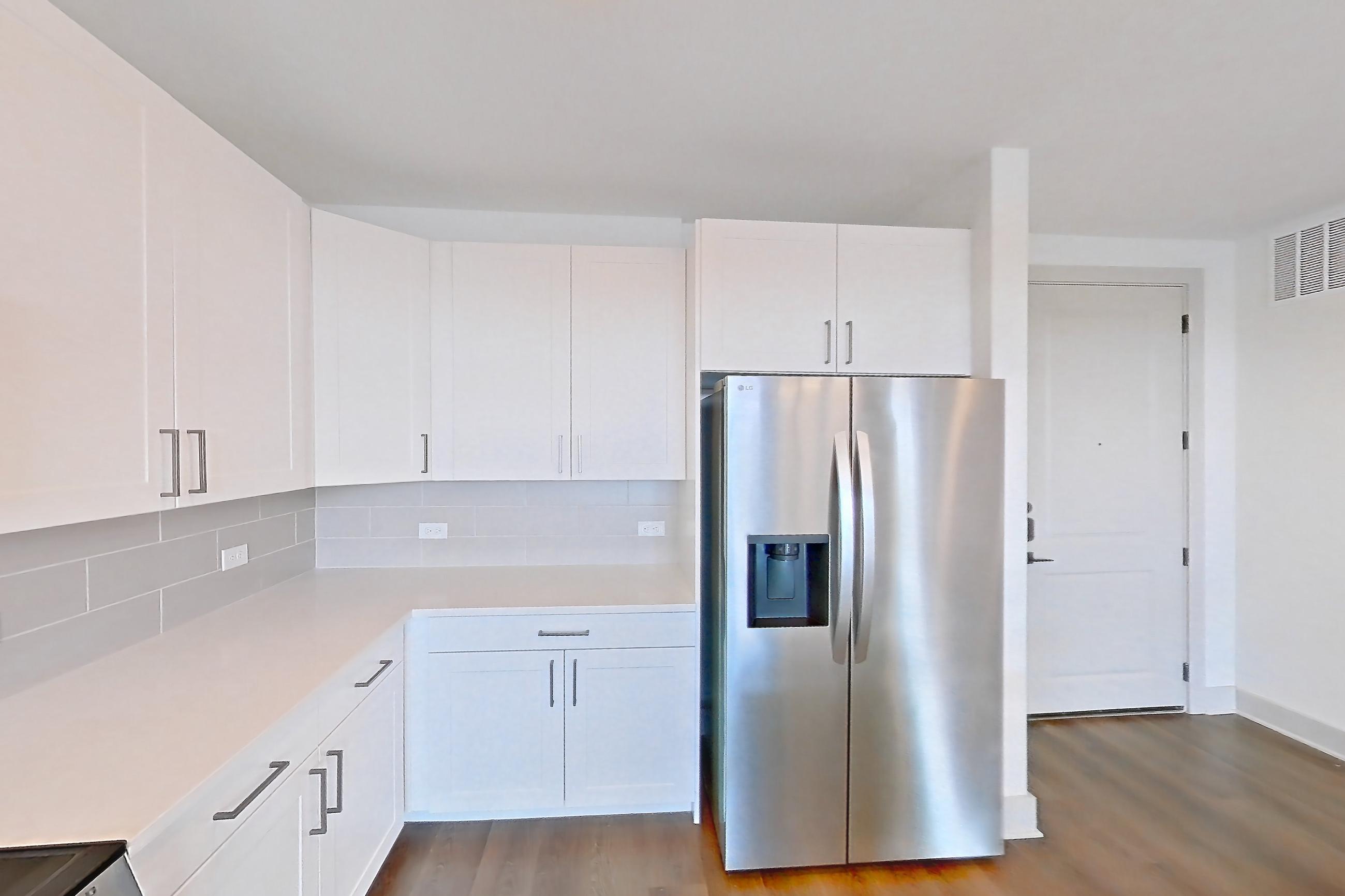 Kitchen with dark wood-finish flooring, electric range, light countertops, oven/range, refrigerator, stainless steel appliances, and water & ice dispenser, Apartment 2304 at Groves South Congress
