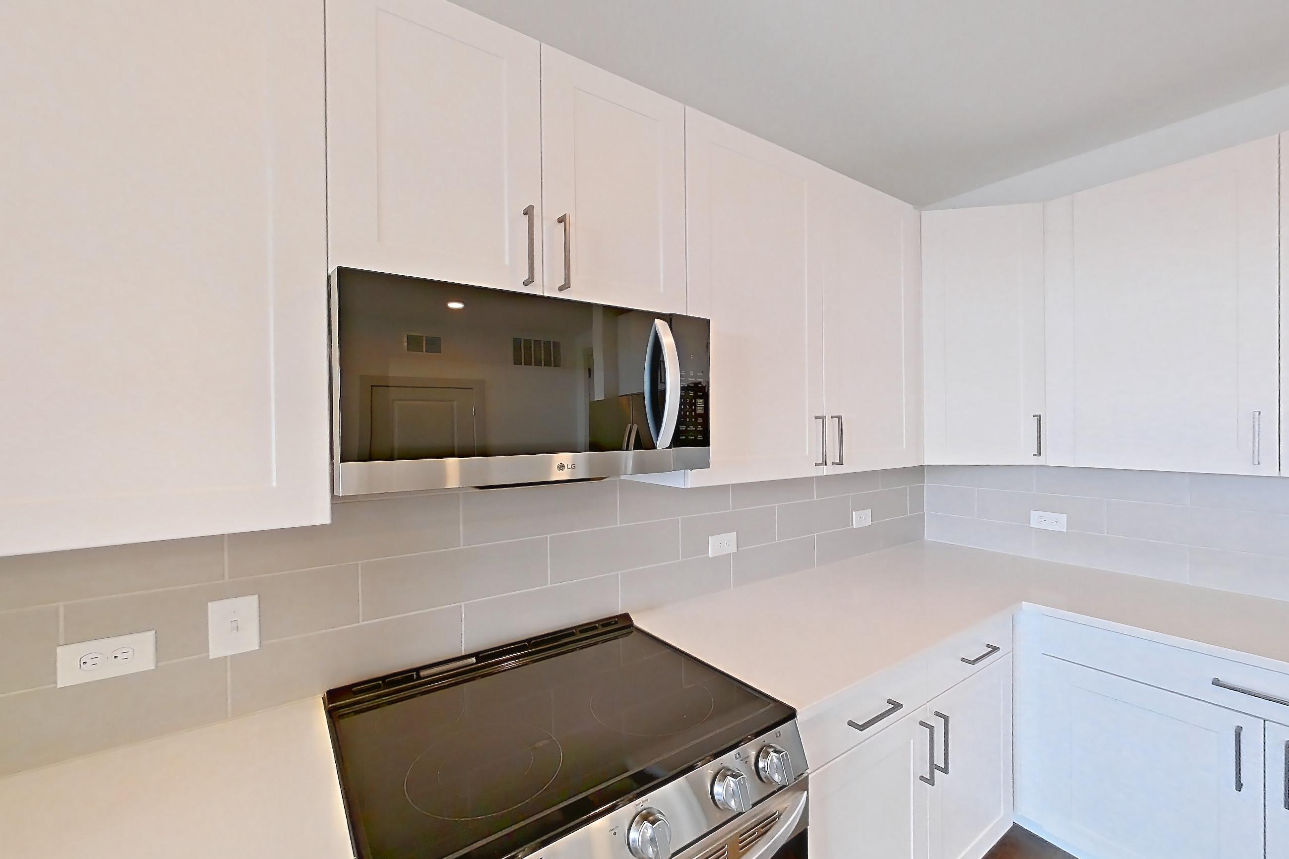 Kitchen with dark wood-finish flooring, electric range, light countertops, oven/range, refrigerator, stainless steel appliances, and water & ice dispenser, Apartment 2304 at Groves South Congress