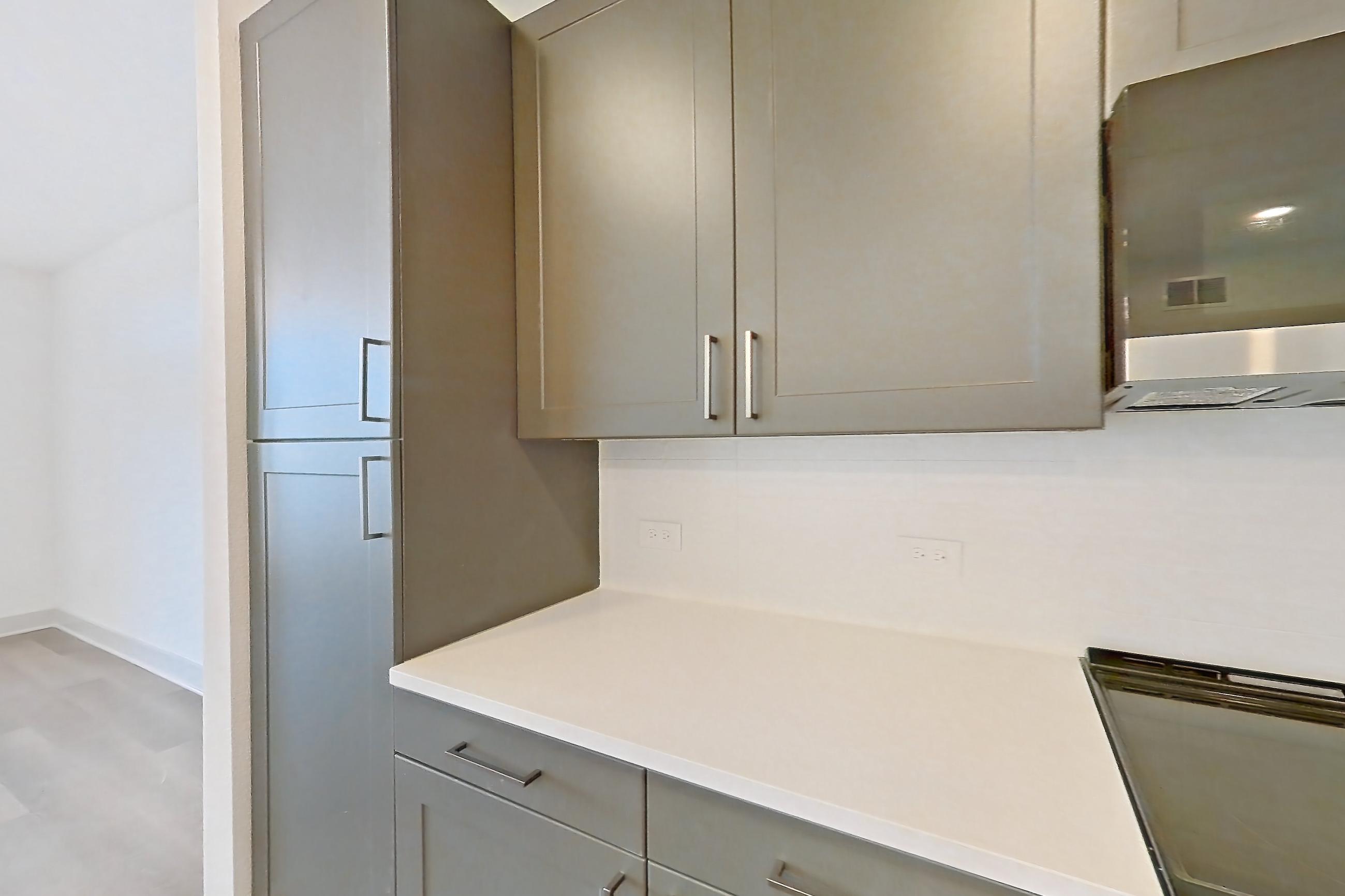 Kitchen with dishwasher, electric range, kitchen island, light countertops, light stone countertops, light wood-finish flooring, oven/range, and stainless steel appliances, Apartment 2406 at Groves South Congress