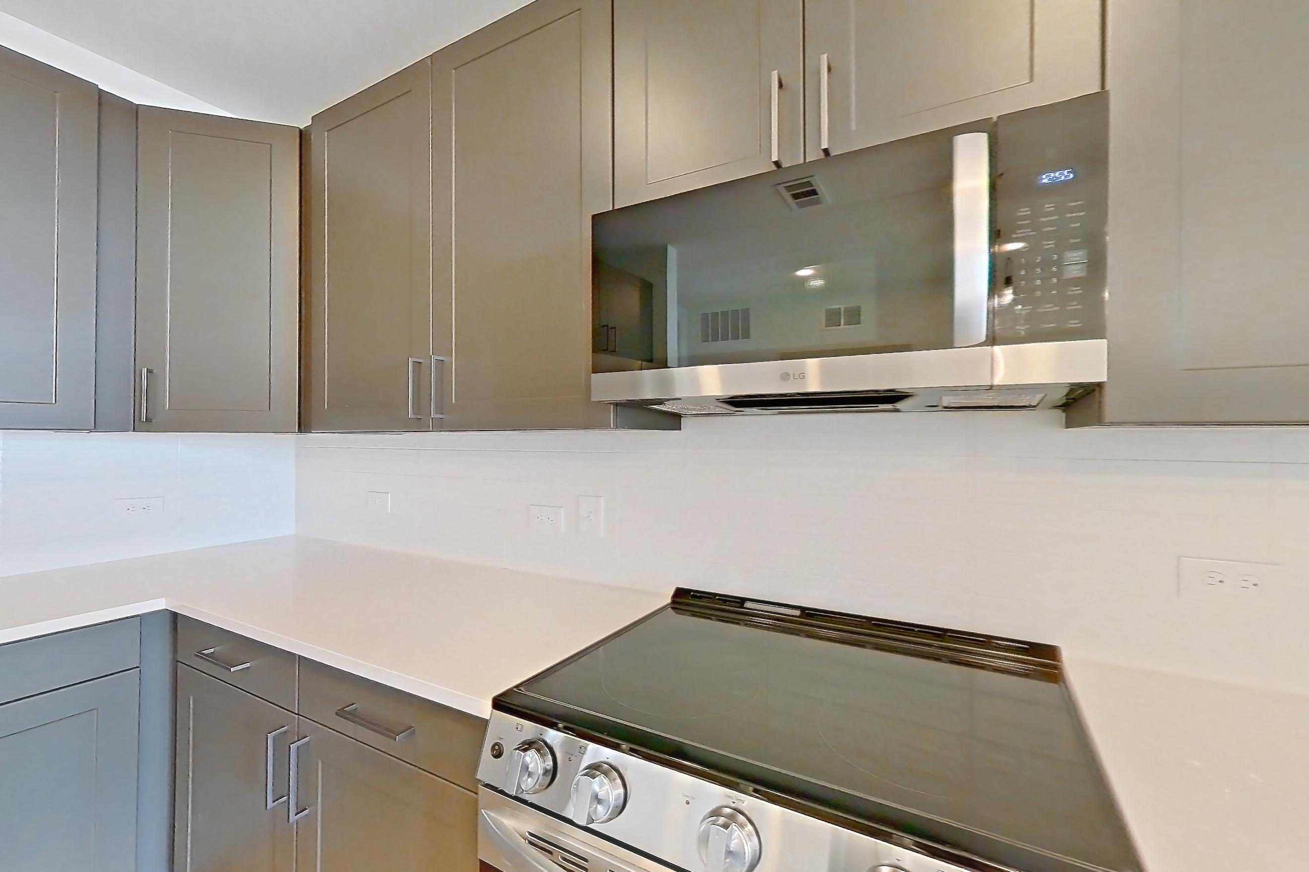 Kitchen with dishwasher, electric range, light countertops, light stone countertops, light wood-finish flooring, microwave, oven/range, and stainless steel appliances, Apartment 2408 at Groves South Congress