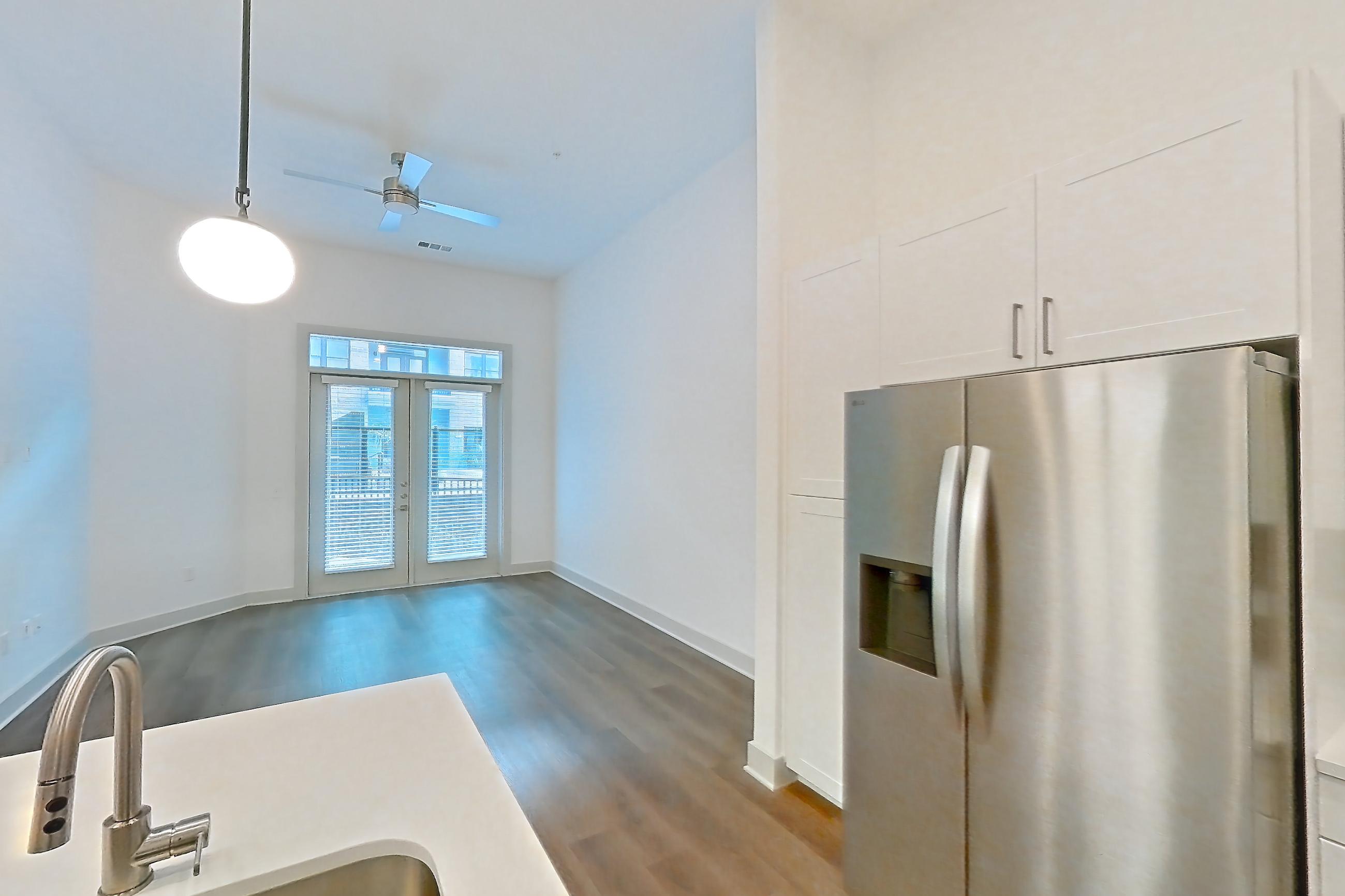 Kitchen with dark wood-finish flooring, electric range, light countertops, light stone countertops, microwave, oven/range, refrigerator, stainless steel appliances, and water & ice dispenser, Apartment 2145 at Groves South Congress