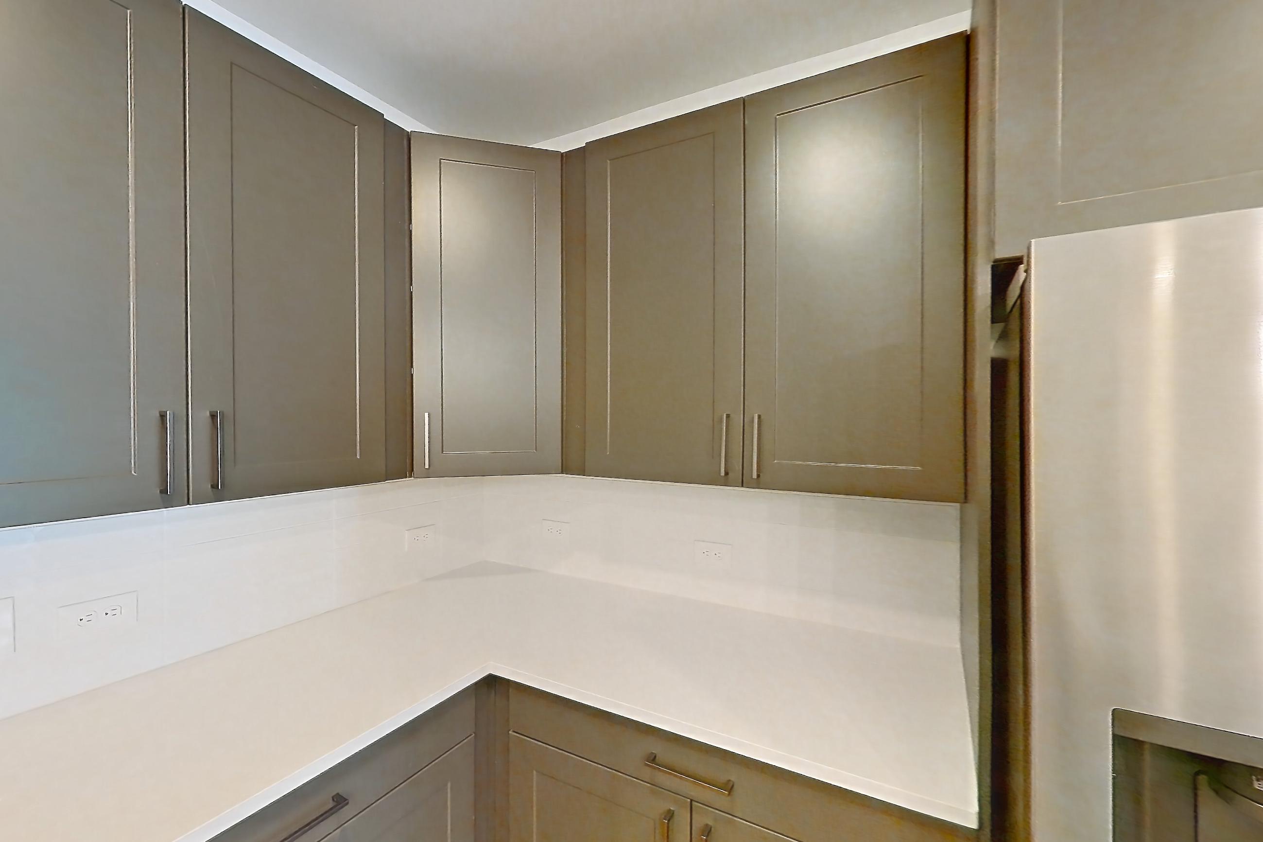 Kitchen with electric range, kitchen island, light countertops, light stone countertops, light wood-finish flooring, oven/range, range hood, refrigerator, stainless steel appliances, and water & ice dispenser, Apartment 2250 at Groves South Congress