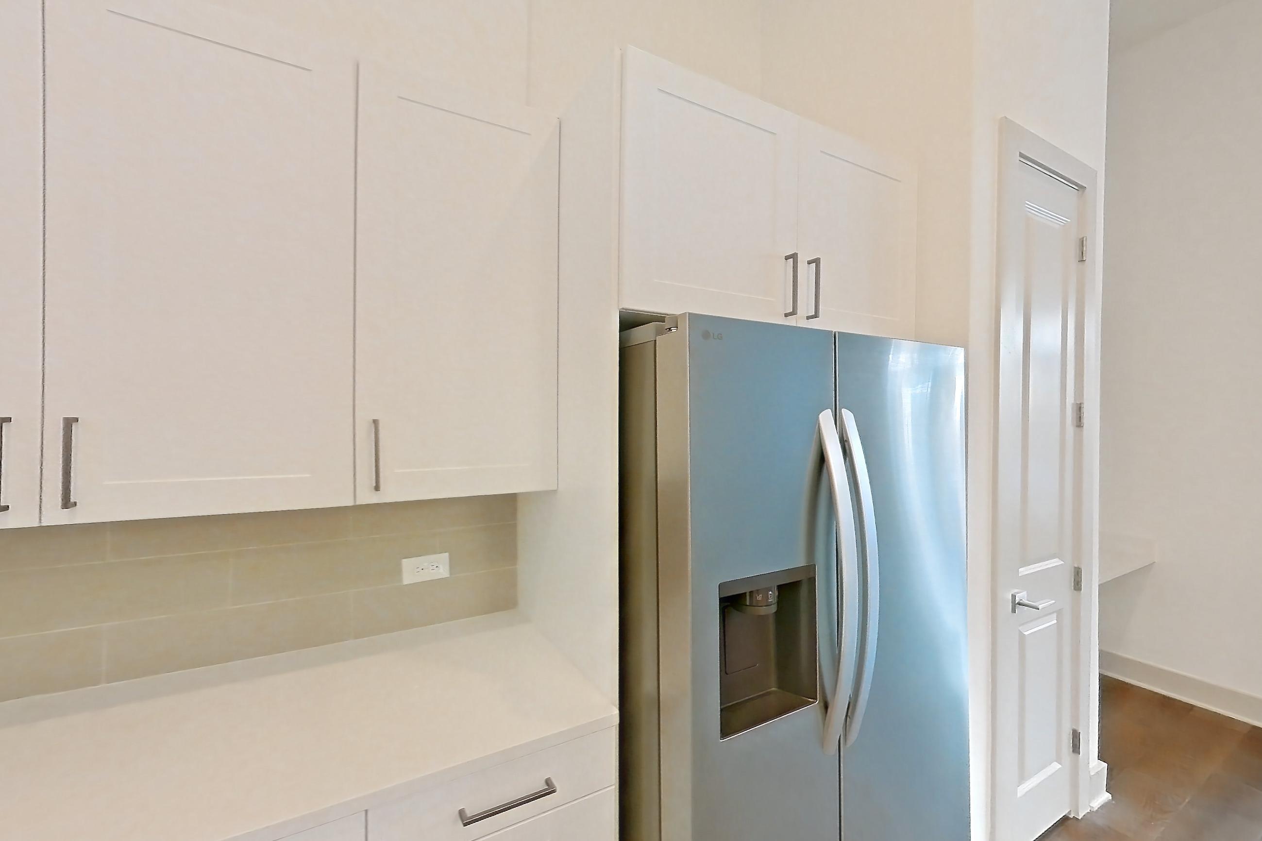 Kitchen with dark wood-finish flooring, electric range, kitchen island, light countertops, light stone countertops, microwave, oven/range, refrigerator, stainless steel appliances, and water & ice dispenser, Apartment 2152 at Groves South Congress