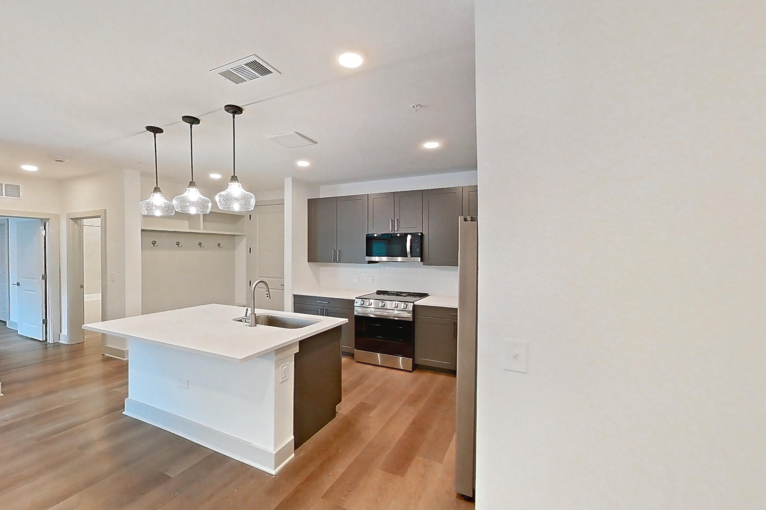 Dining room with electric range, light countertops, light stone countertops, light wood-finish flooring, oven/range, and stainless steel appliances, Apartment 2254 at Groves South Congress