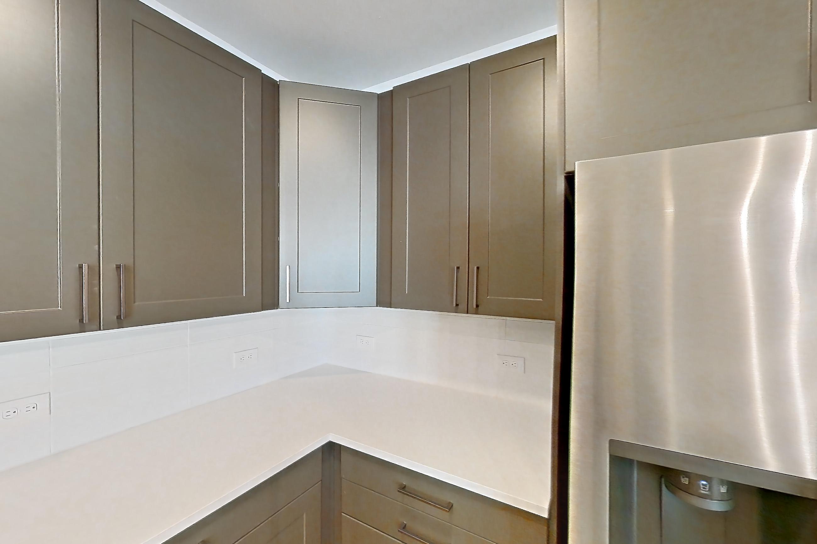 Kitchen with electric range, kitchen island, light countertops, light stone countertops, light wood-finish flooring, microwave, oven/range, range hood, refrigerator, stainless steel appliances, and water & ice dispenser, Apartment 2254 at Groves South Congress