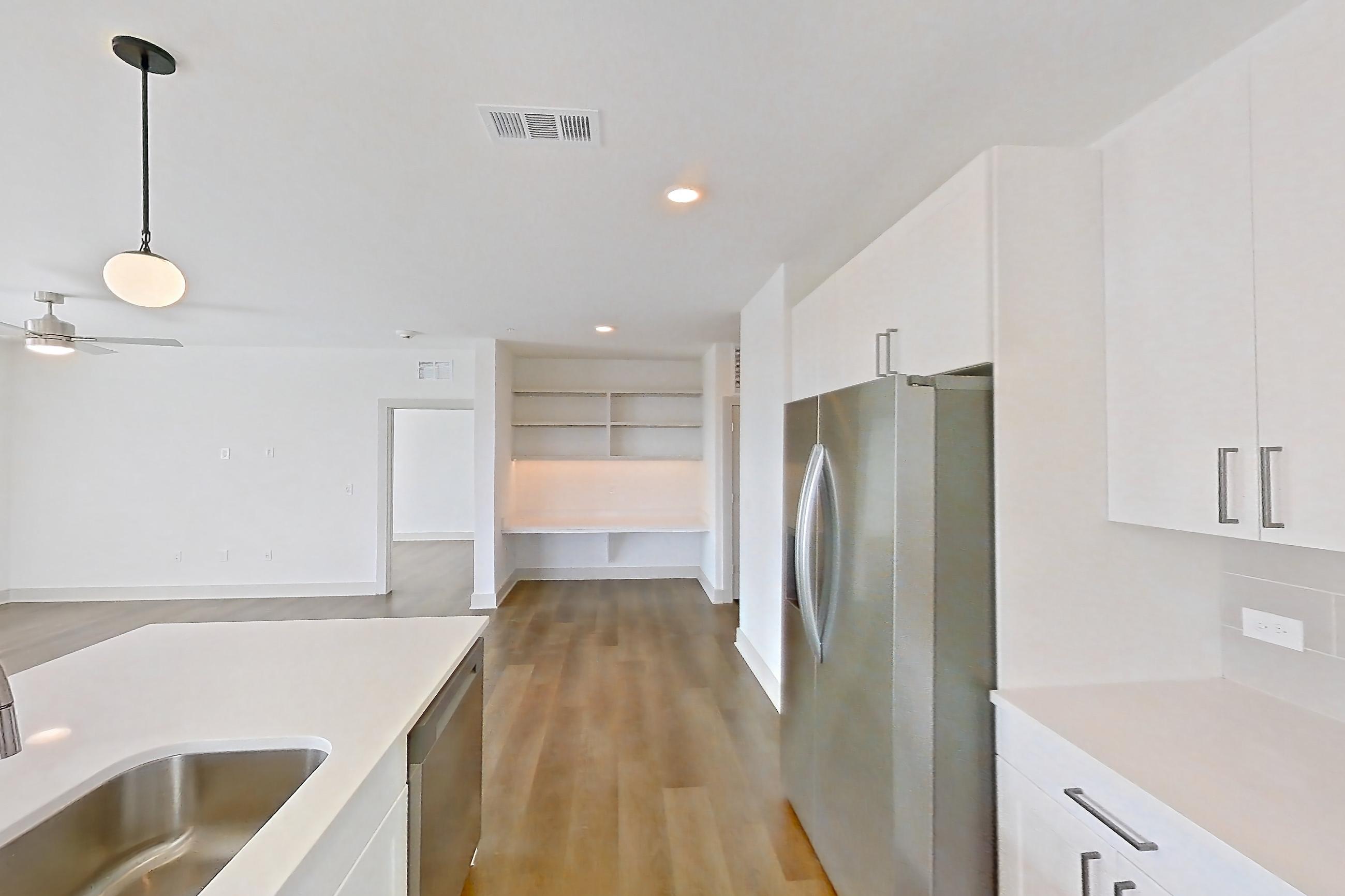 Kitchen with dark wood-finish flooring, electric range, light countertops, light stone countertops, microwave, oven/range, refrigerator, and stainless steel appliances, Apartment 2301 at Groves South Congress
