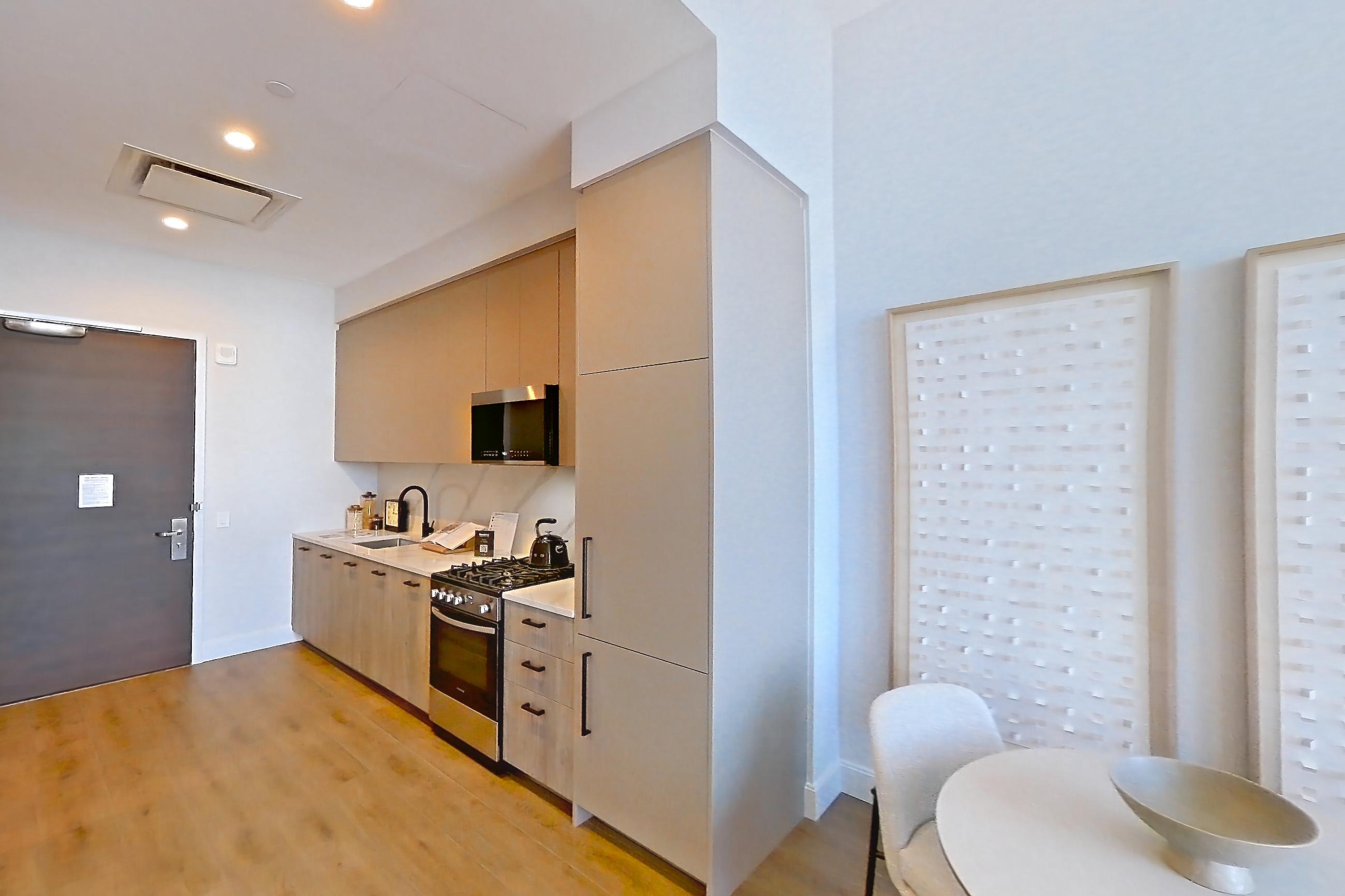 Living room with gas range, light wood-finish flooring, oven/range, and stainless steel appliances, Apartment PH2G at Lumen