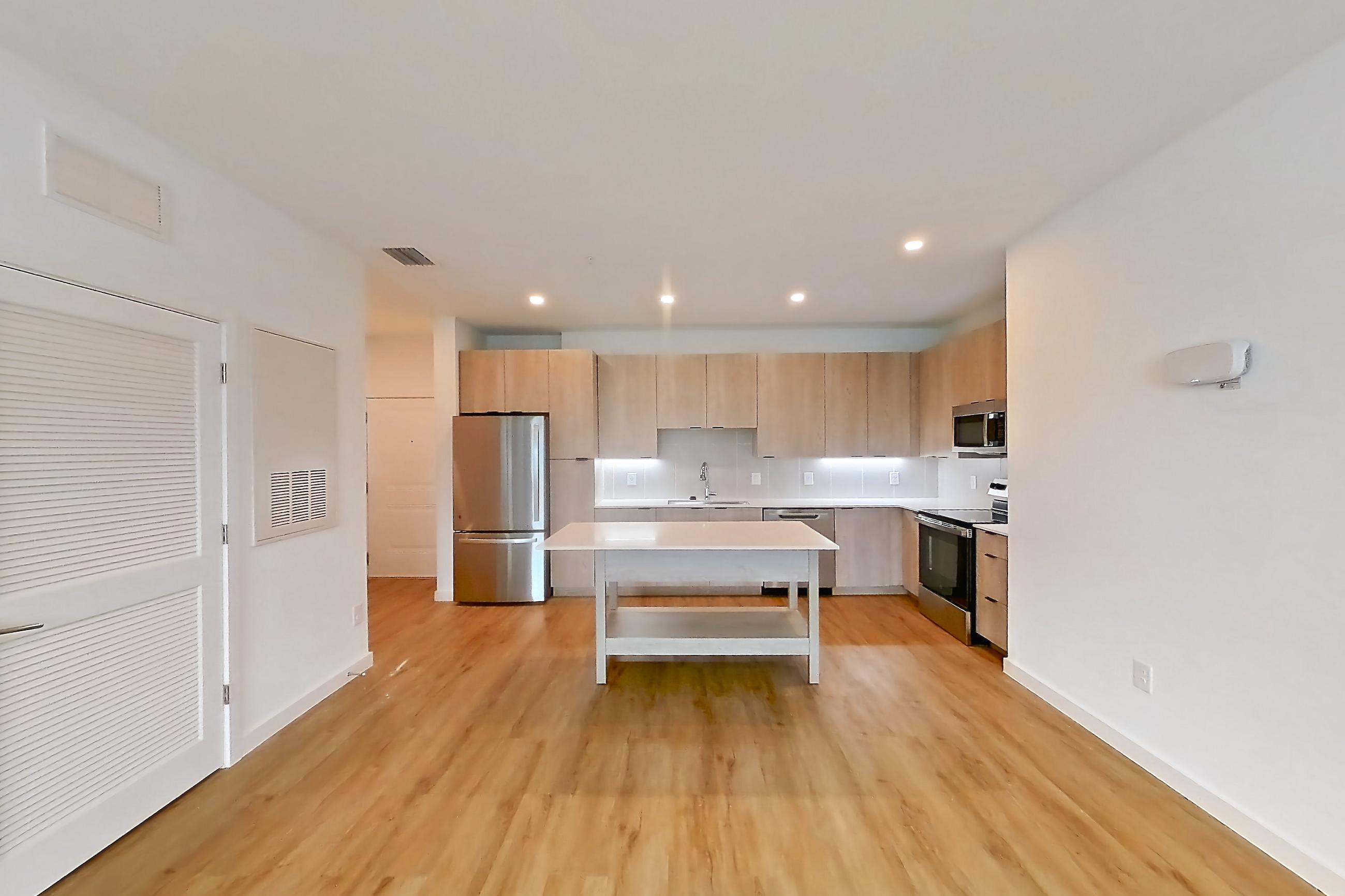 Living space with dishwasher, electric range, light countertops, light wood-finish flooring, oven/range, refrigerator, and stainless steel appliances, Apartment 1109 at Caroline Anclote Harbor