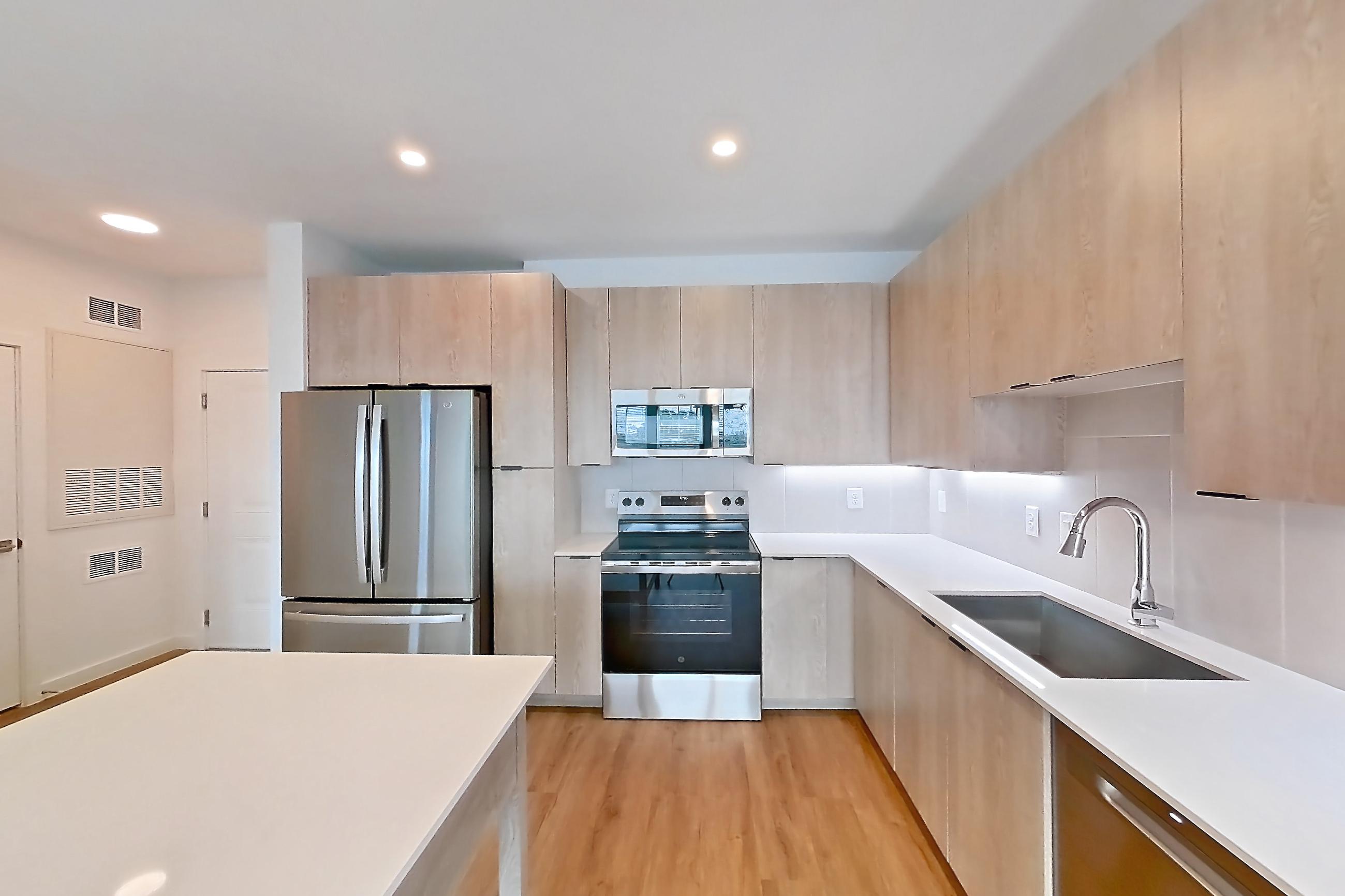 Kitchen with dishwasher, electric range, light countertops, light wood-finish flooring, oven/range, refrigerator, and stainless steel appliances, Apartment 1202 at Caroline Anclote Harbor