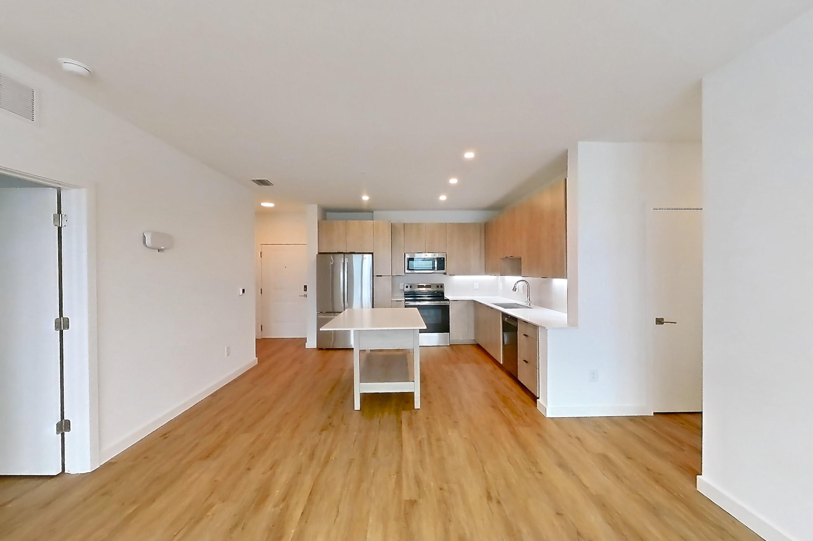 Living space with dishwasher, electric range, light countertops, light wood-finish flooring, oven/range, refrigerator, and stainless steel appliances, Apartment 1202 at Caroline Anclote Harbor
