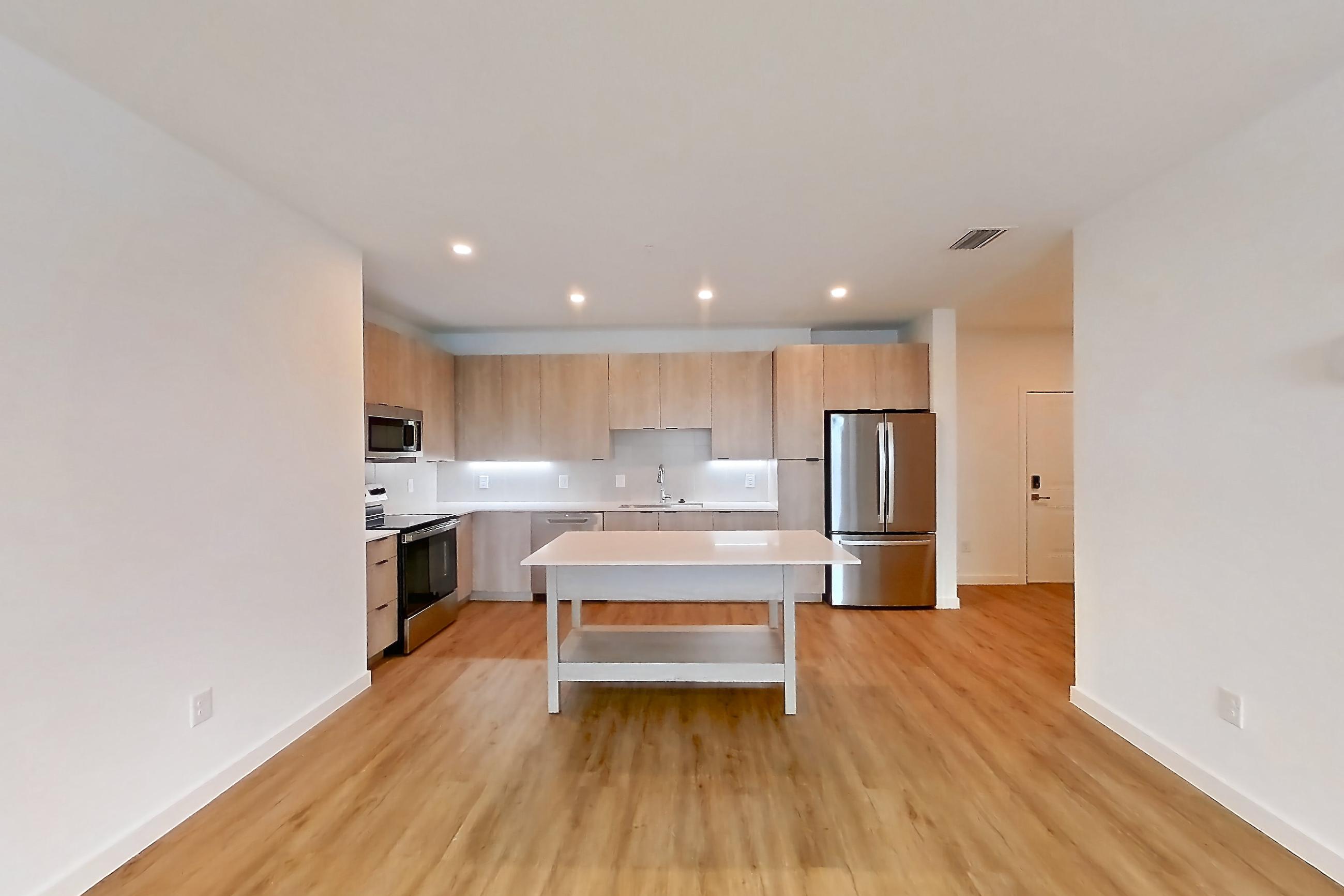 Living space with dishwasher, electric range, light countertops, light wood-finish flooring, oven/range, refrigerator, and stainless steel appliances, Apartment 1204 at Caroline Anclote Harbor