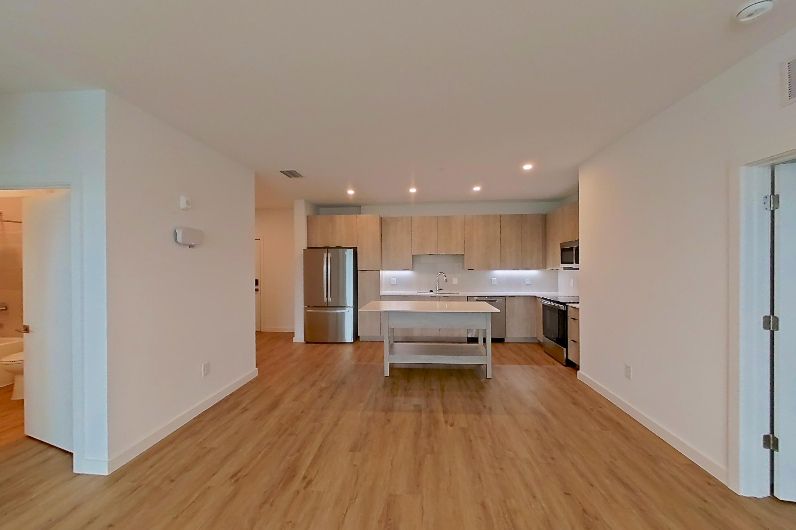 Living space with dishwasher, electric range, light countertops, light wood-finish flooring, oven/range, refrigerator, and stainless steel appliances, Apartment 1209 at Caroline Anclote Harbor