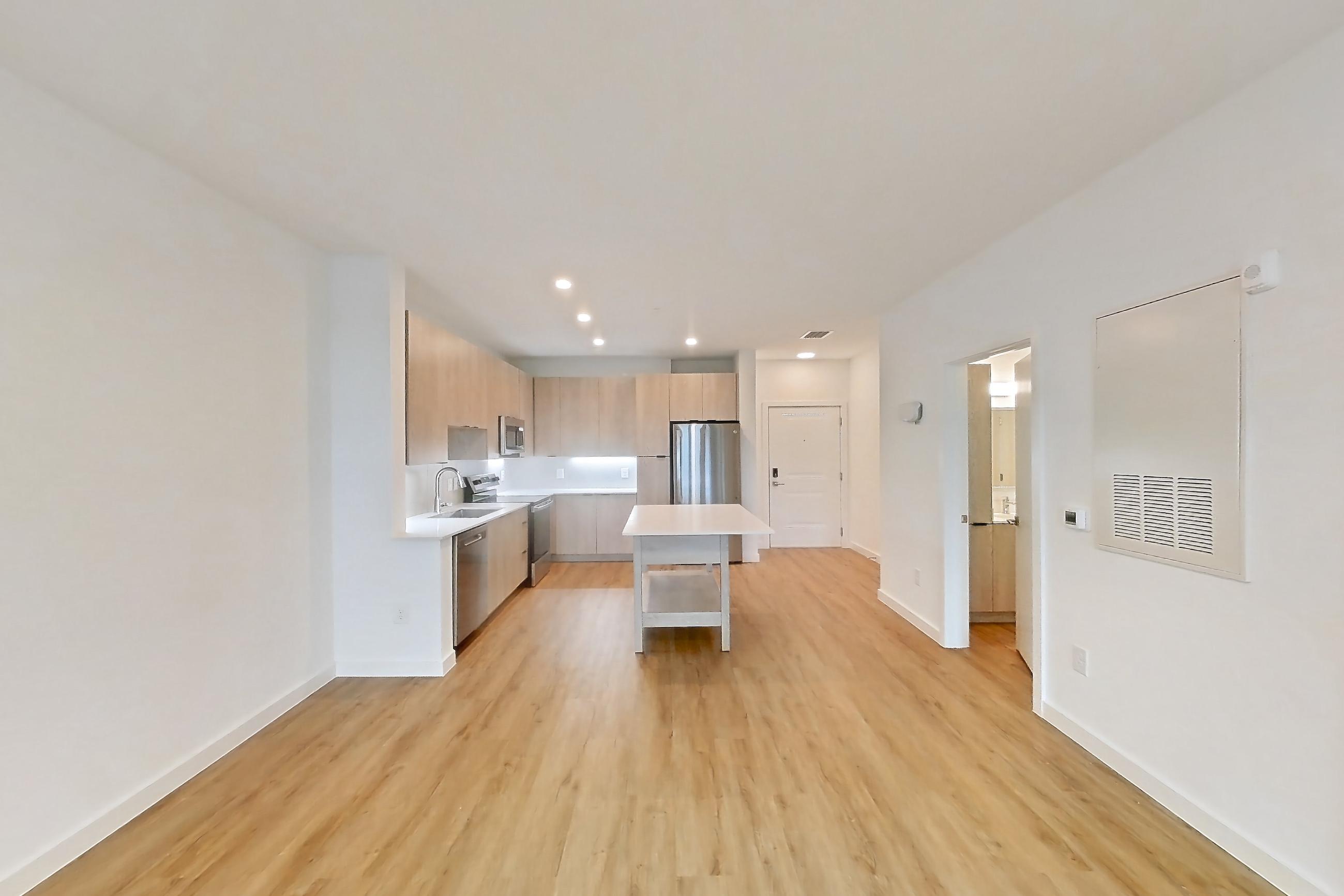 Living space with dishwasher, electric range, light countertops, light wood-finish flooring, oven/range, and stainless steel appliances, Apartment 1210 at Caroline Anclote Harbor