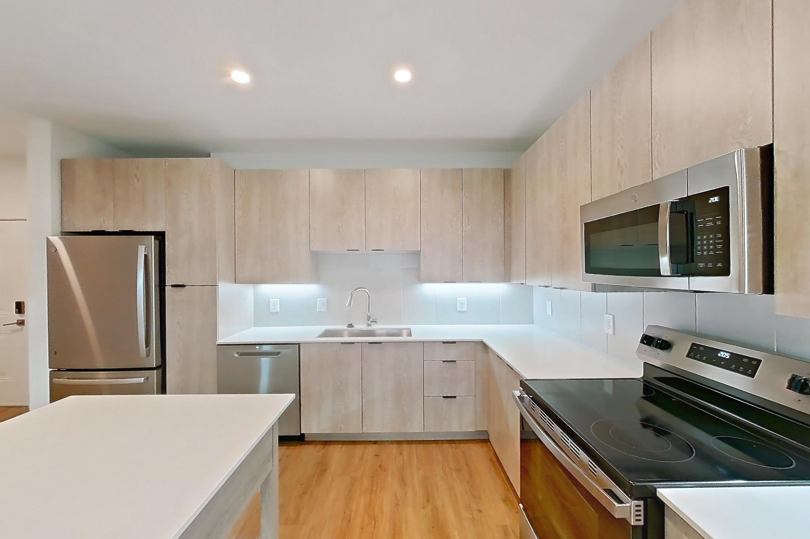 Kitchen with dishwasher, electric range, light countertops, light wood-finish flooring, oven/range, and stainless steel appliances, Apartment 1212 at Caroline Anclote Harbor