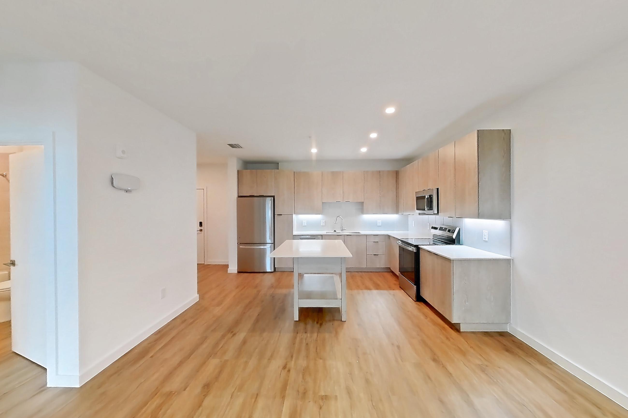 Living space with electric range, light countertops, light wood-finish flooring, oven/range, refrigerator, and stainless steel appliances, Apartment 1212 at Caroline Anclote Harbor