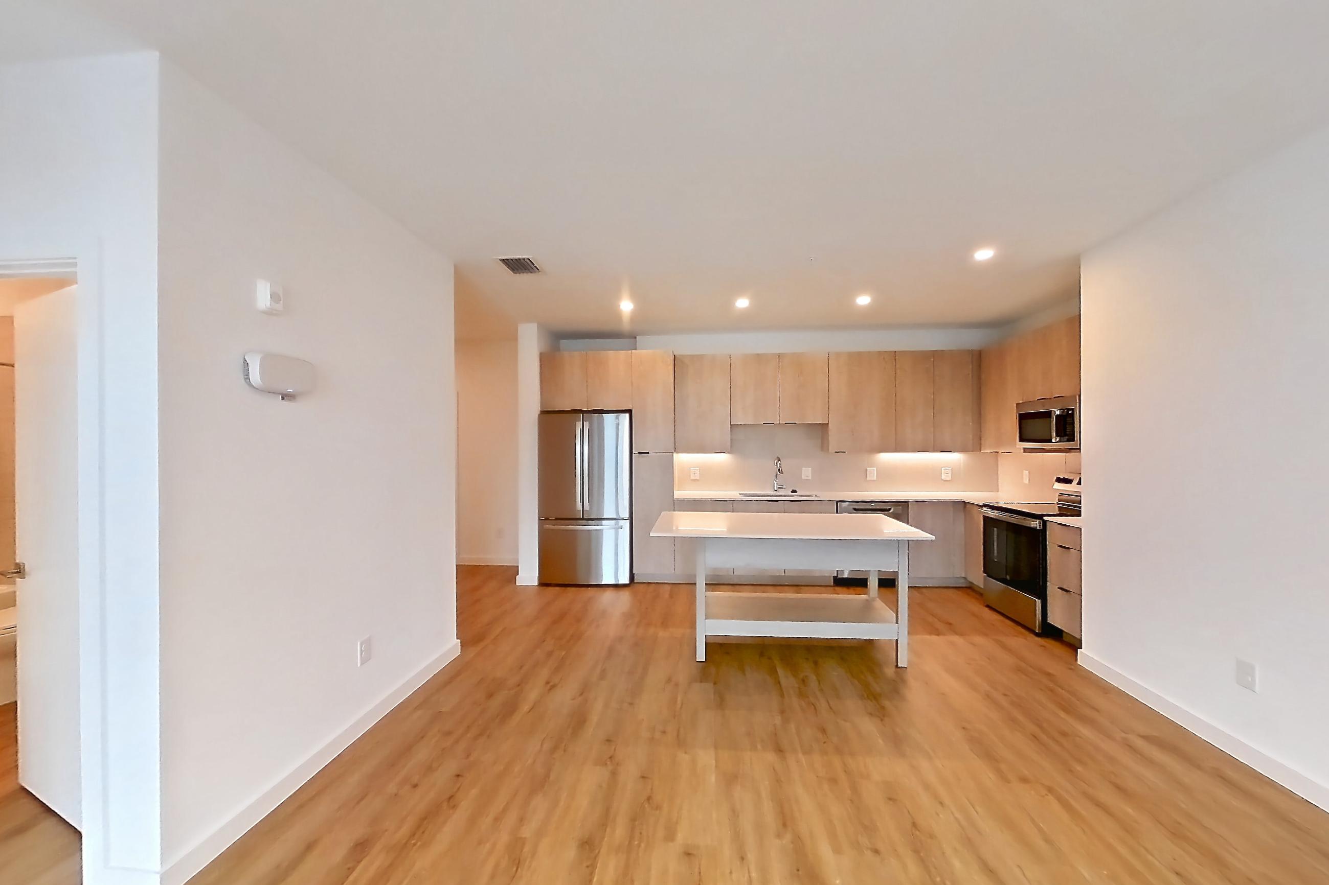 Living space with electric range, light countertops, light wood-finish flooring, oven/range, refrigerator, and stainless steel appliances, Apartment 1213 at Caroline Anclote Harbor