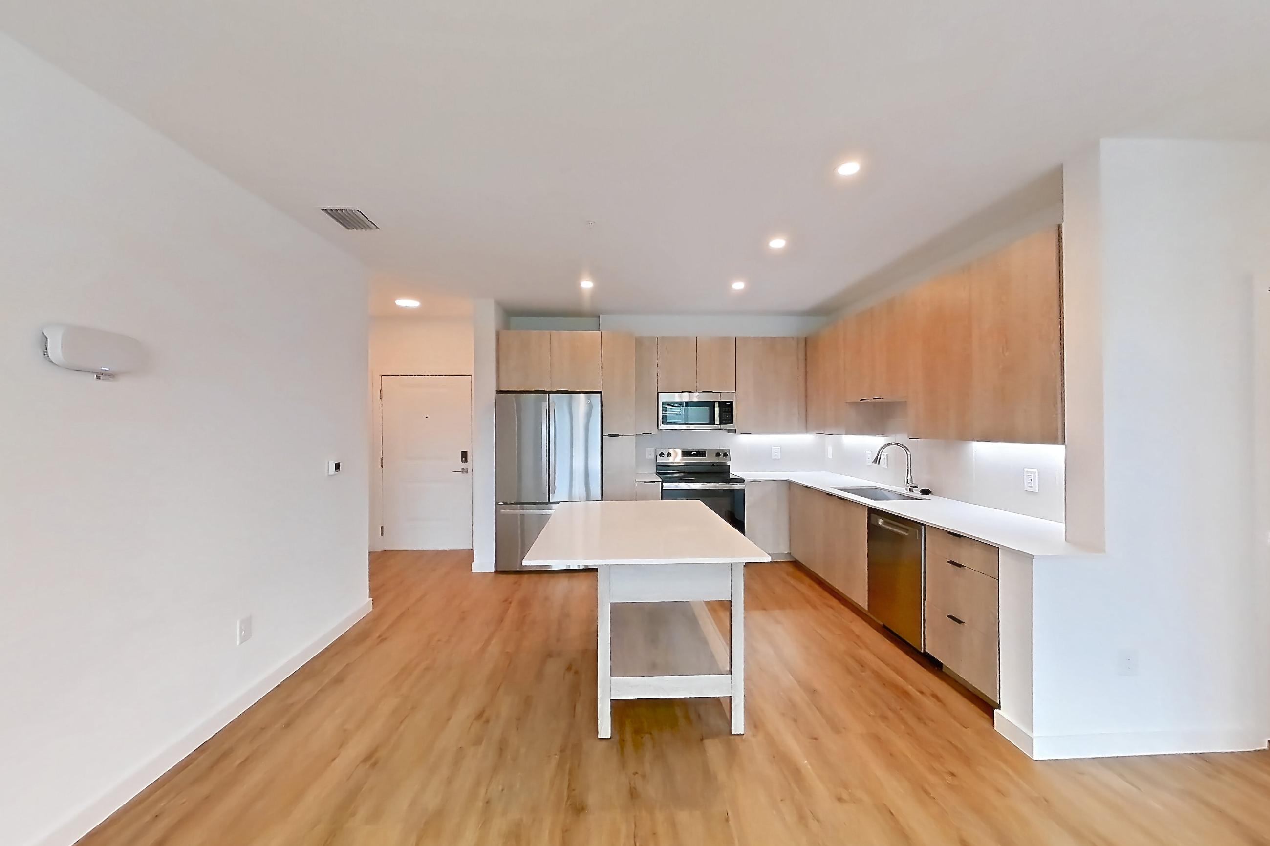 Living space with dishwasher, electric range, light countertops, light wood-finish flooring, oven/range, refrigerator, and stainless steel appliances, Apartment 1215 at Caroline Anclote Harbor
