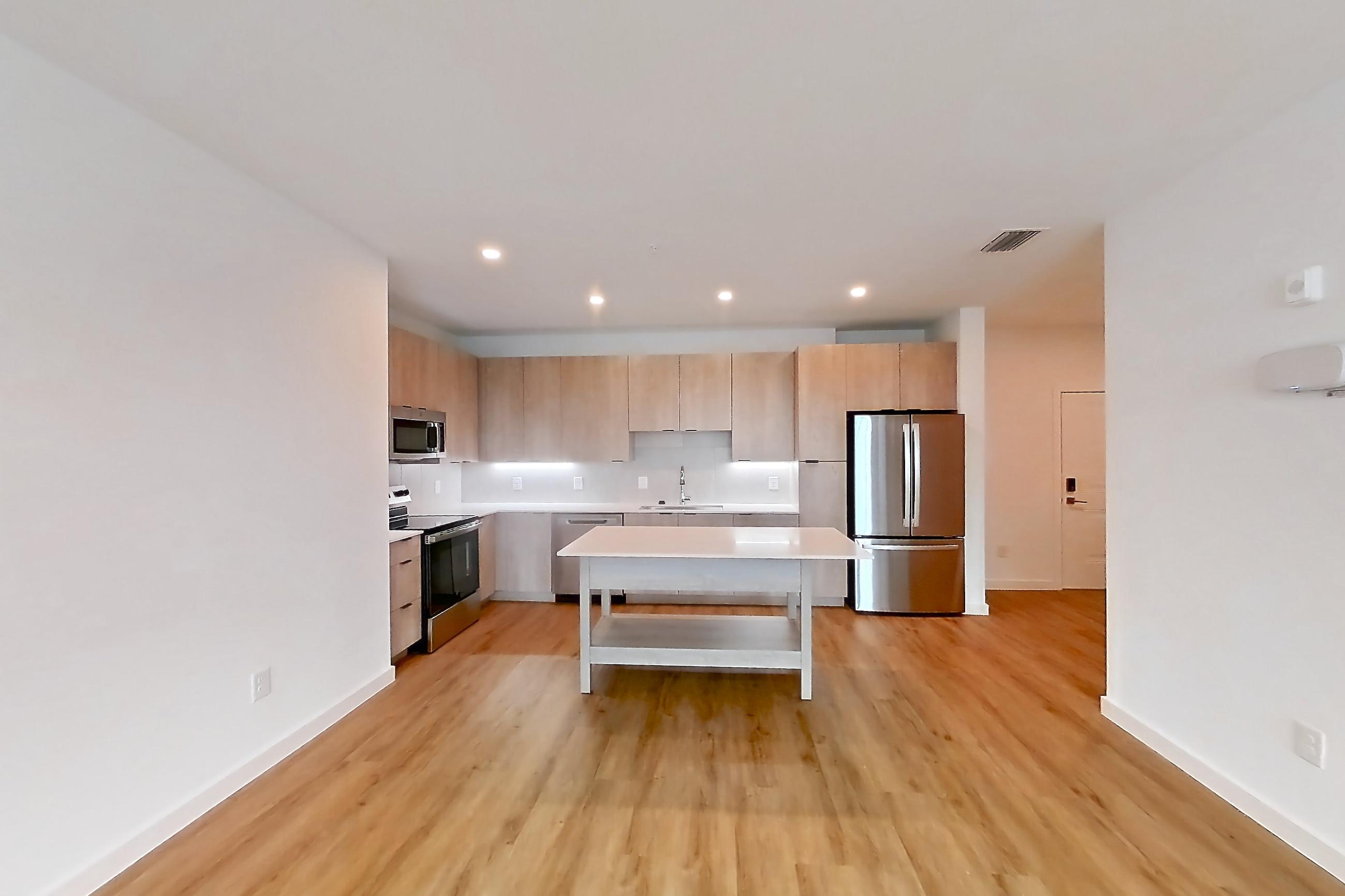Living space with dishwasher, electric range, light countertops, light wood-finish flooring, oven/range, refrigerator, and stainless steel appliances, Apartment 1219 at Caroline Anclote Harbor