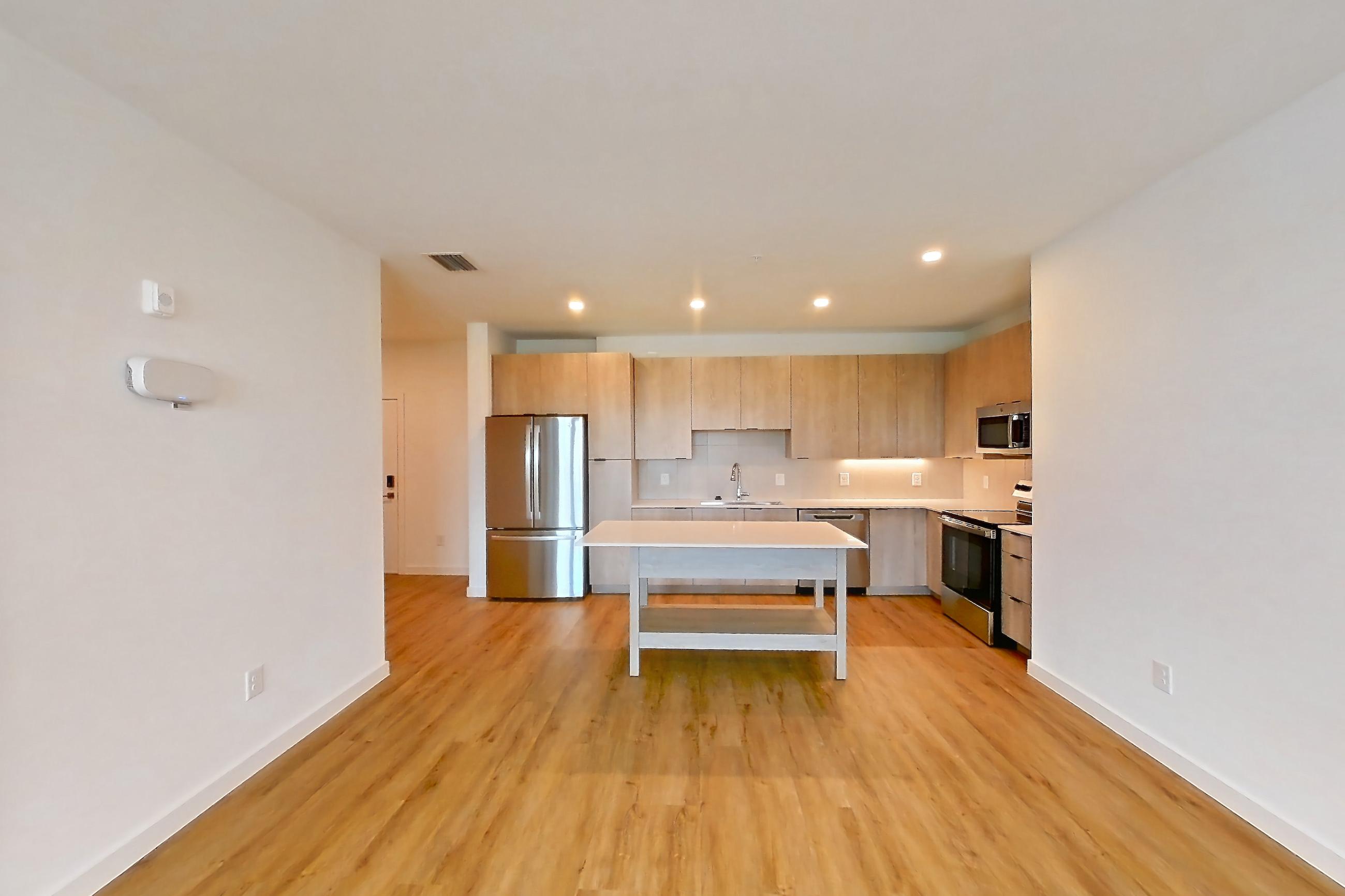 Living space with dishwasher, electric range, light countertops, light wood-finish flooring, oven/range, refrigerator, and stainless steel appliances, Apartment 1301 at Caroline Anclote Harbor