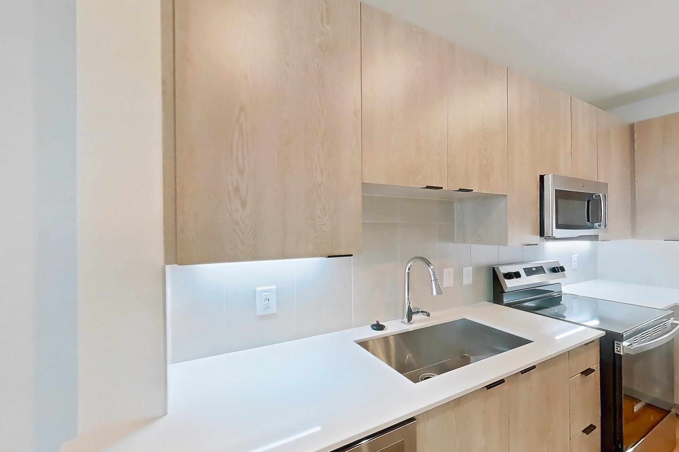Kitchen with dishwasher, electric range, light countertops, light wood-finish flooring, oven/range, refrigerator, and stainless steel appliances, Apartment 1310 at Caroline Anclote Harbor