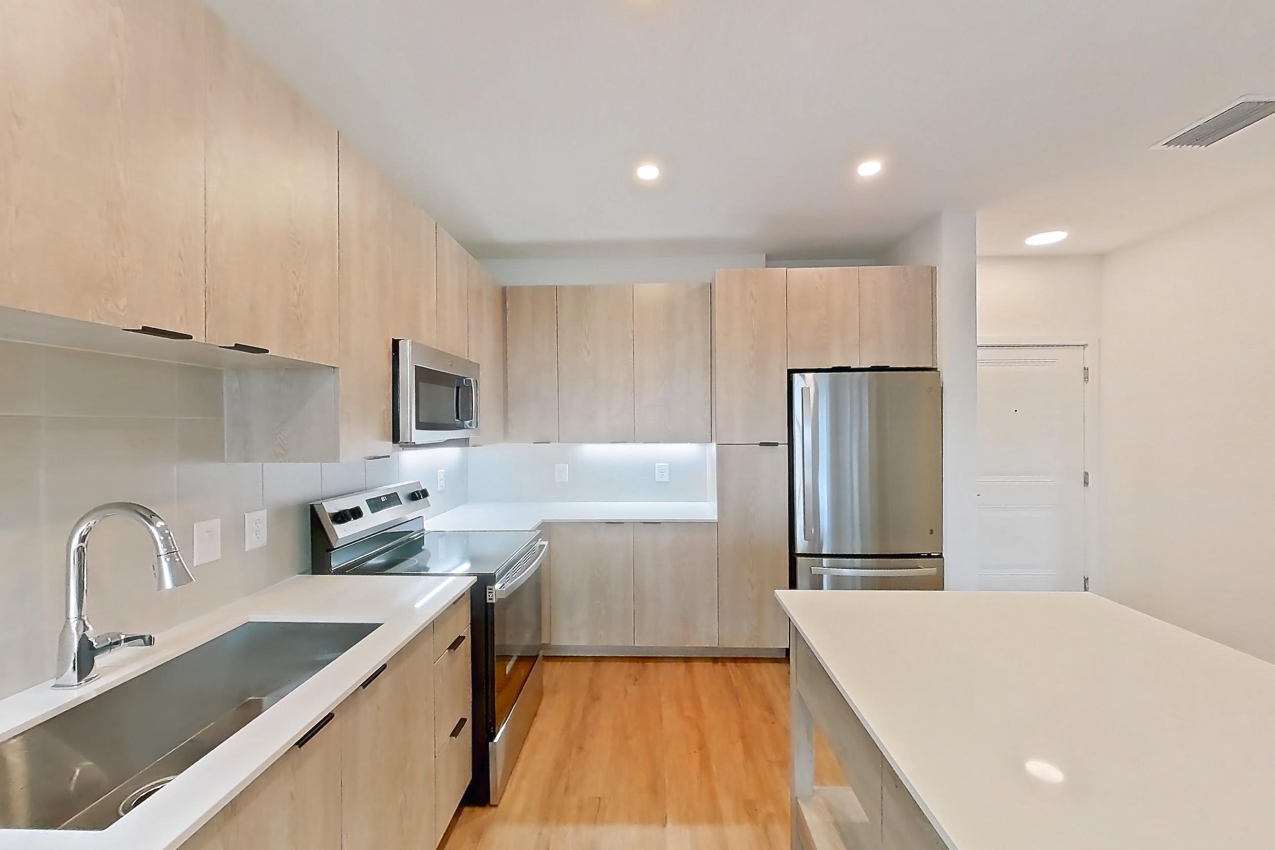 Kitchen with dishwasher, electric range, light countertops, light wood-finish flooring, oven/range, refrigerator, and stainless steel appliances, Apartment 1310 at Caroline Anclote Harbor