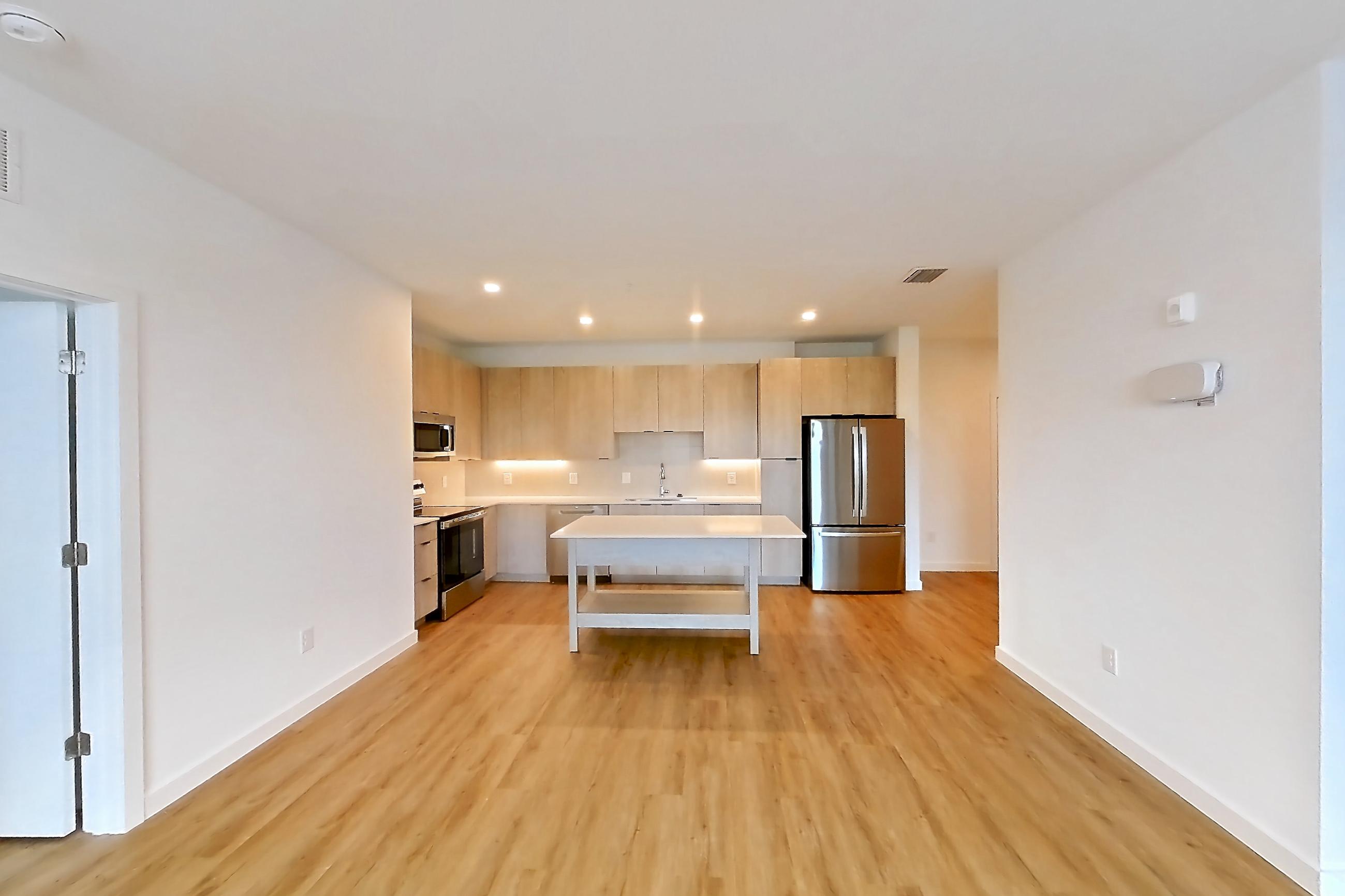 Living space with dishwasher, electric range, light countertops, light wood-finish flooring, oven/range, refrigerator, and stainless steel appliances, Apartment 1311 at Caroline Anclote Harbor