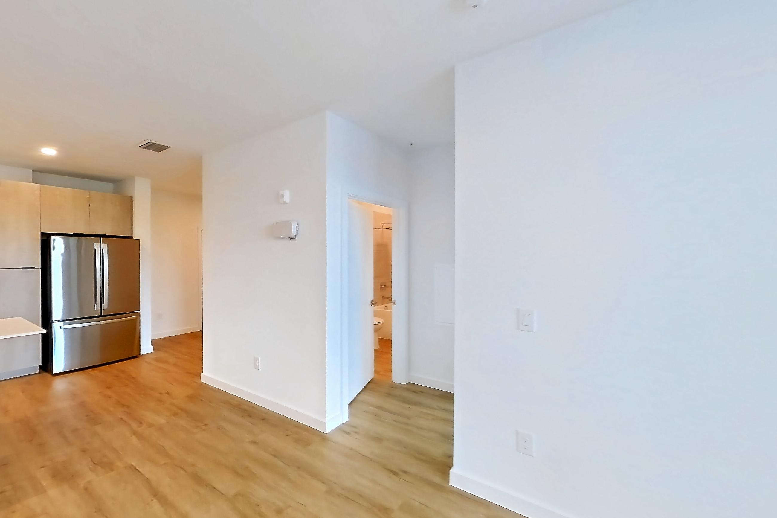 Living space with dishwasher, electric range, light countertops, light wood-finish flooring, oven/range, refrigerator, and stainless steel appliances, Apartment 1311 at Caroline Anclote Harbor