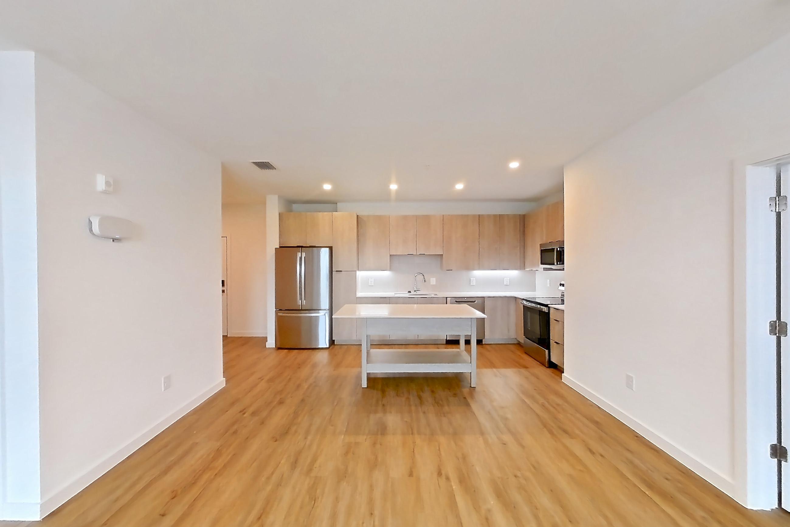 Living space with dishwasher, electric range, light countertops, light wood-finish flooring, oven/range, refrigerator, and stainless steel appliances, Apartment 1313 at Caroline Anclote Harbor