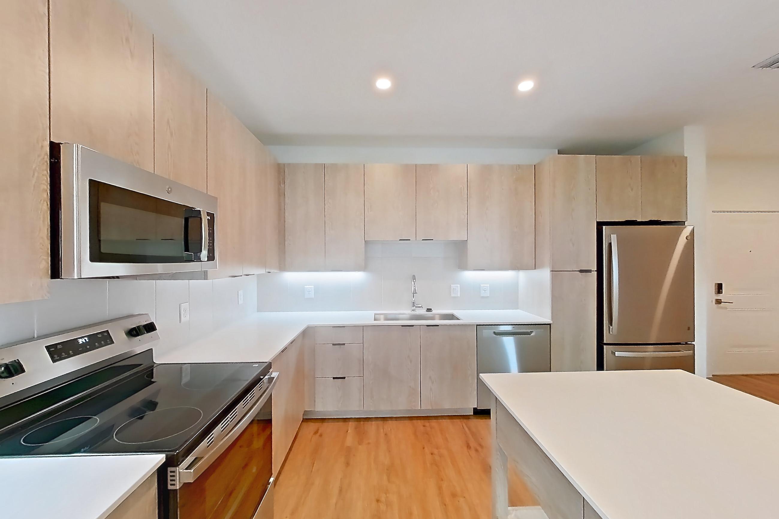 Kitchen with dishwasher, electric range, light countertops, light wood-finish flooring, oven/range, and stainless steel appliances, Apartment 1318 at Caroline Anclote Harbor