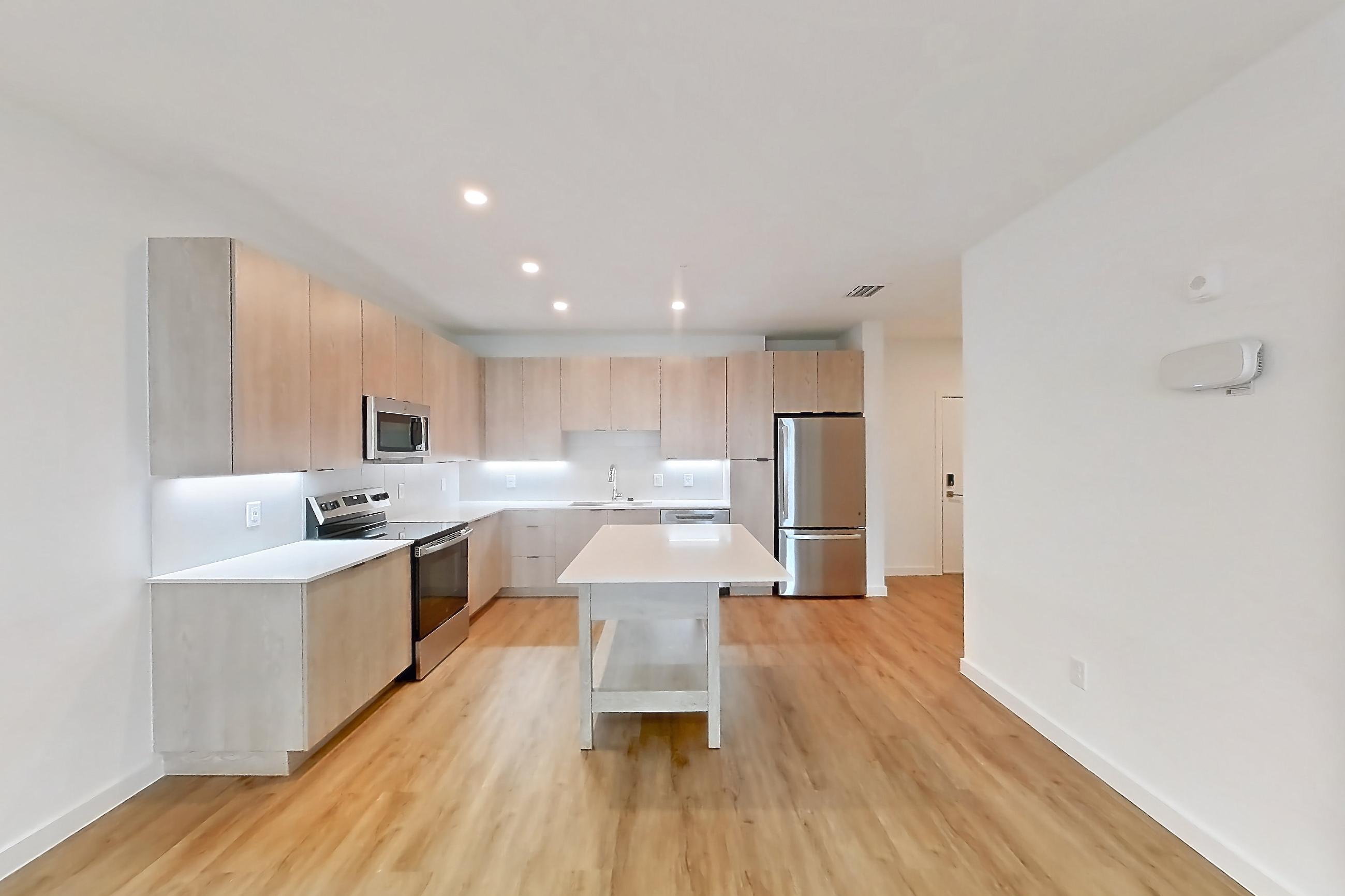 Living space with dishwasher, electric range, light countertops, light wood-finish flooring, oven/range, refrigerator, and stainless steel appliances, Apartment 1318 at Caroline Anclote Harbor