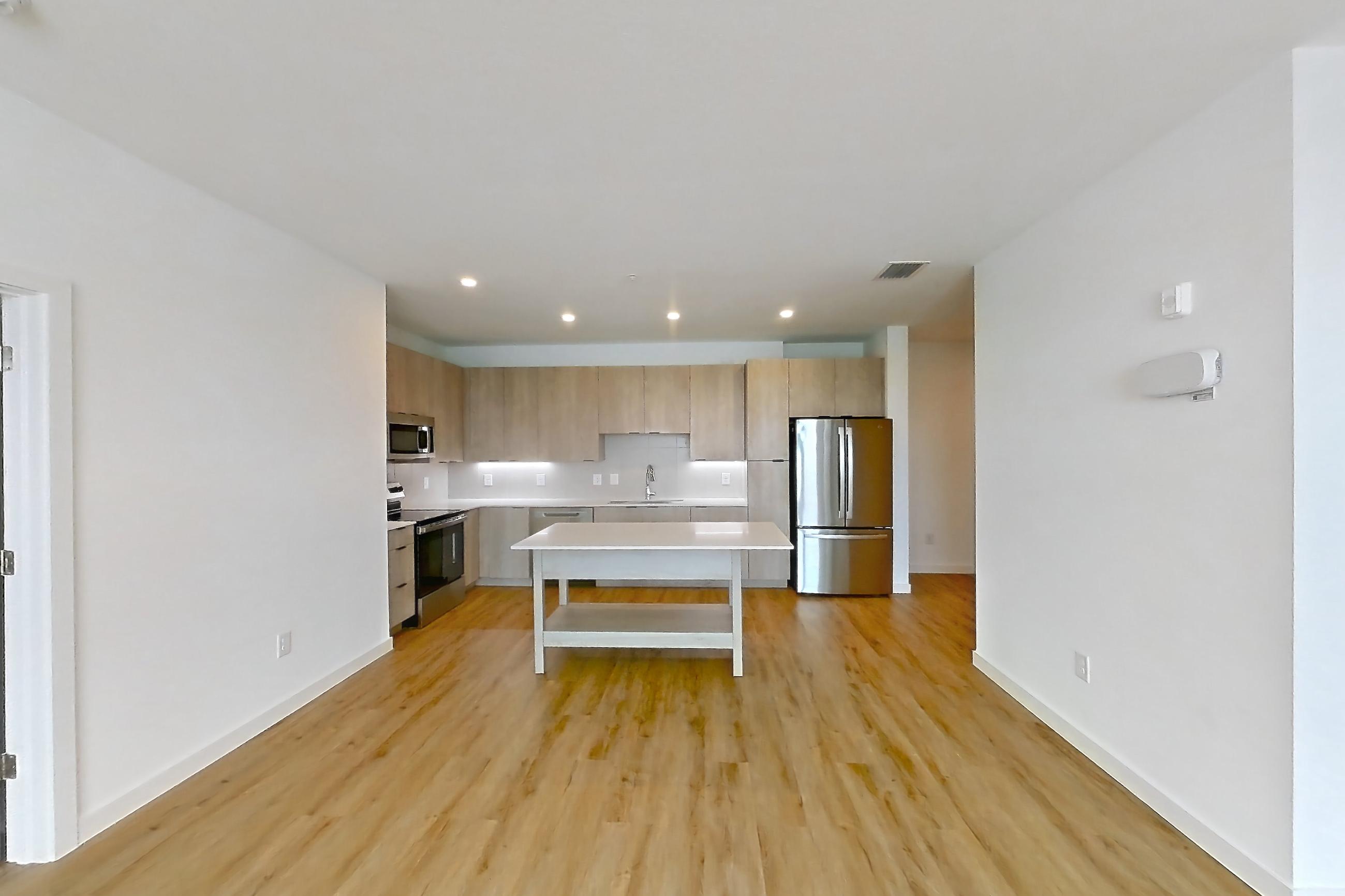 Living space with electric range, light countertops, light wood-finish flooring, oven/range, refrigerator, and stainless steel appliances, Apartment 1404 at Caroline Anclote Harbor