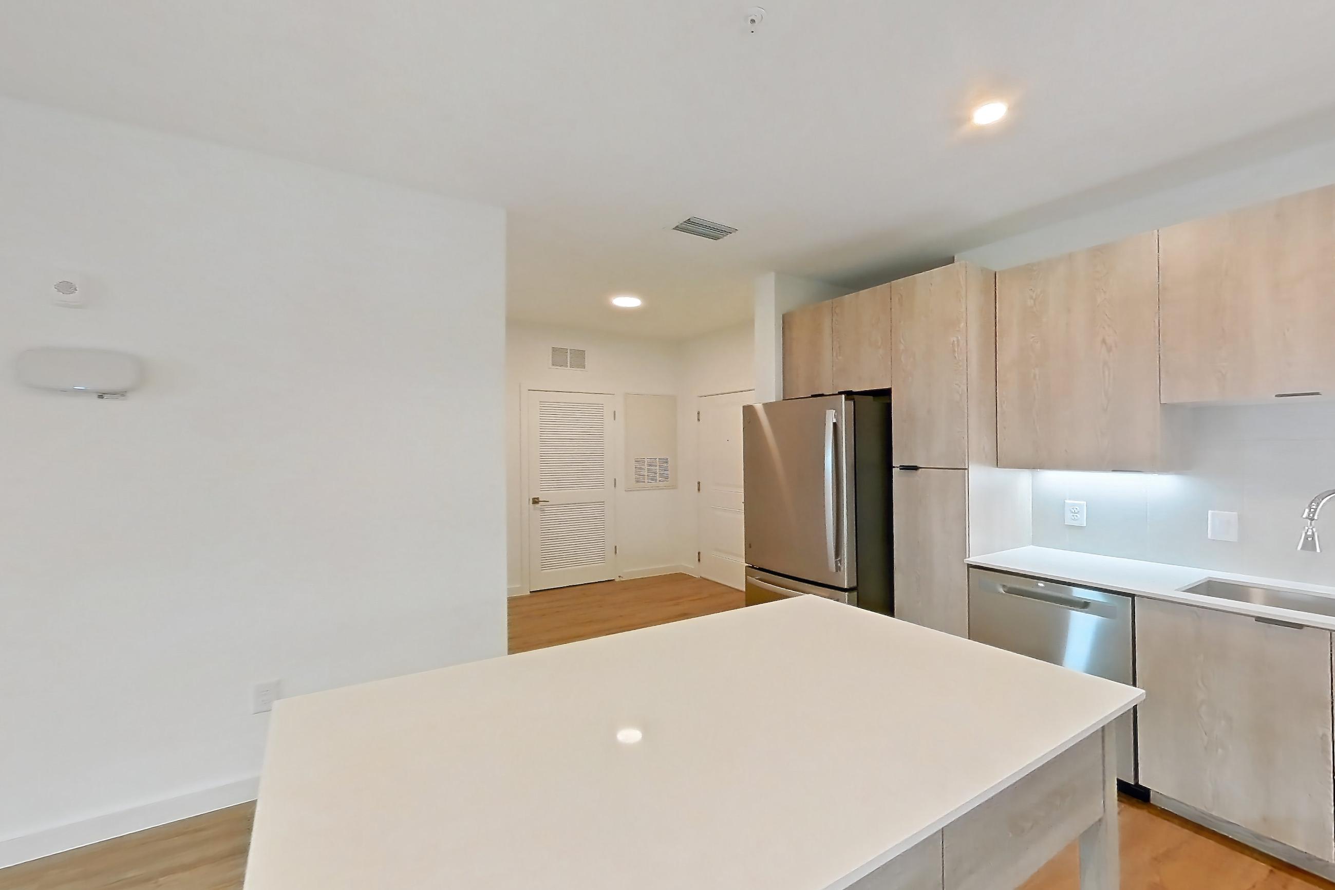 Kitchen with dishwasher, electric range, light countertops, light wood-finish flooring, oven/range, refrigerator, and stainless steel appliances, Apartment 1405 at Caroline Anclote Harbor
