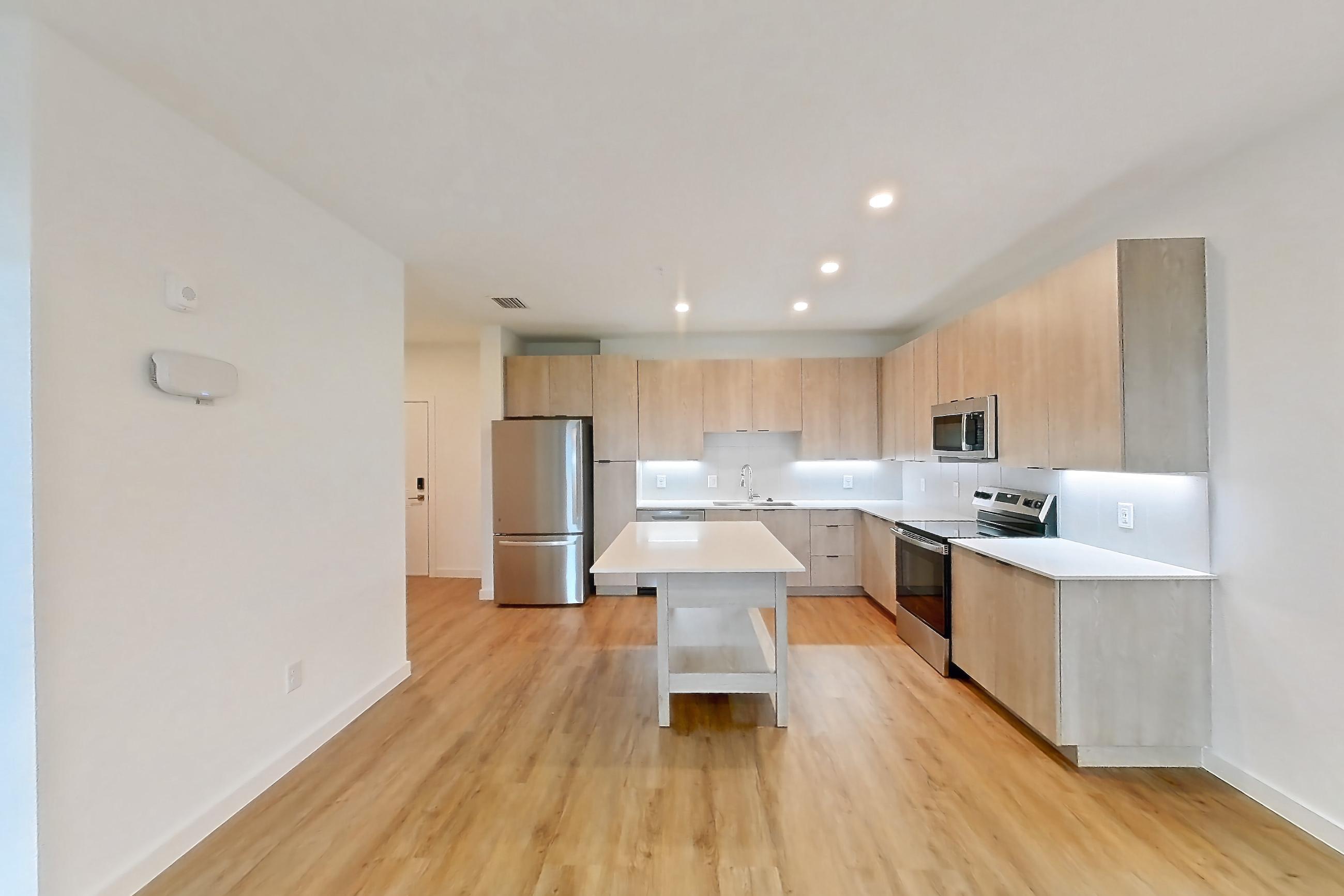 Living space with electric range, light countertops, light wood-finish flooring, oven/range, refrigerator, and stainless steel appliances, Apartment 1405 at Caroline Anclote Harbor