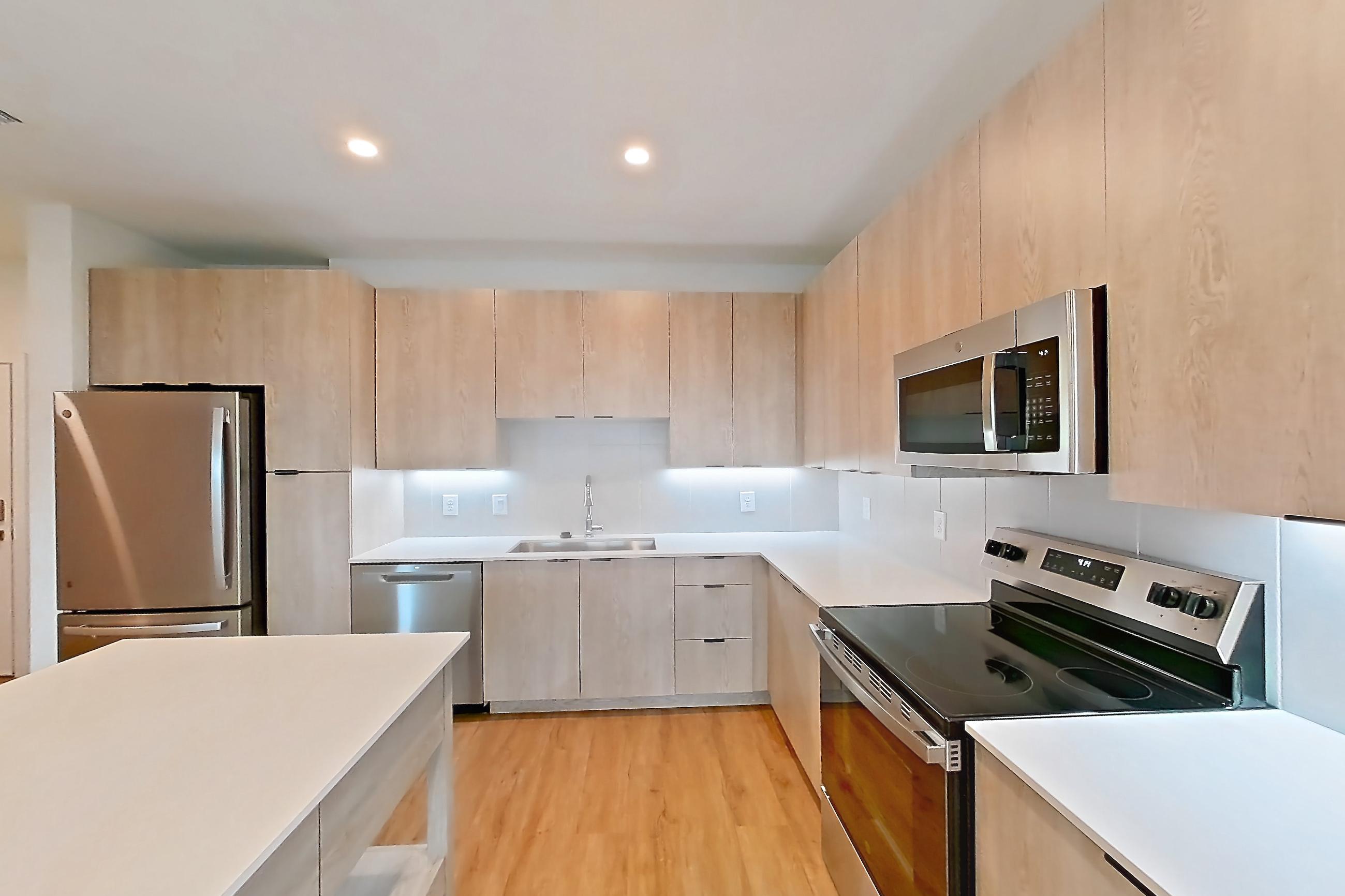 Kitchen with black appliances, dishwasher, electric range, light countertops, light wood-finish flooring, oven/range, refrigerator, and stainless steel appliances, Apartment 1414 at Caroline Anclote Harbor