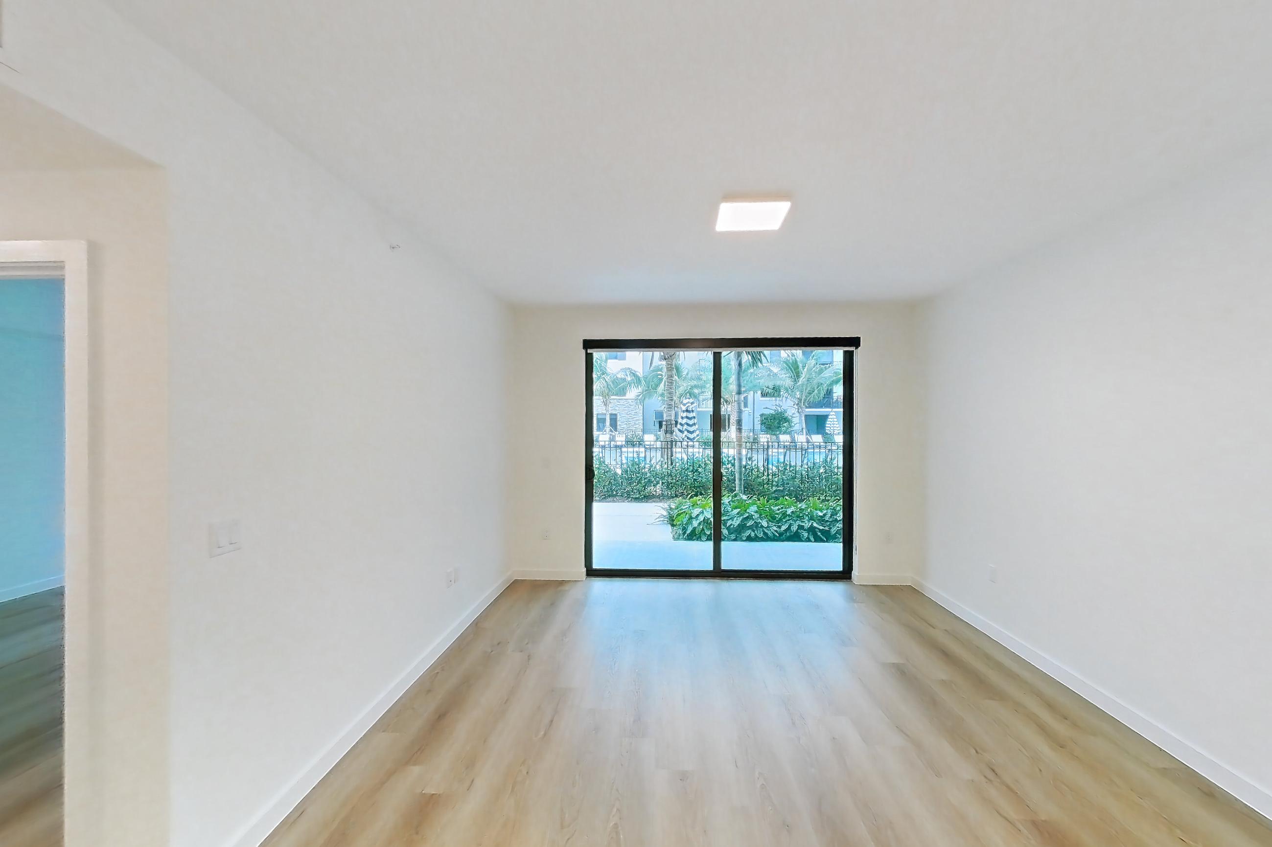 Kitchen island corner with dishwasher, light stone countertops, light wood-finish flooring, and stainless steel appliances, Apartment 101 at Caroline Pompano Beach