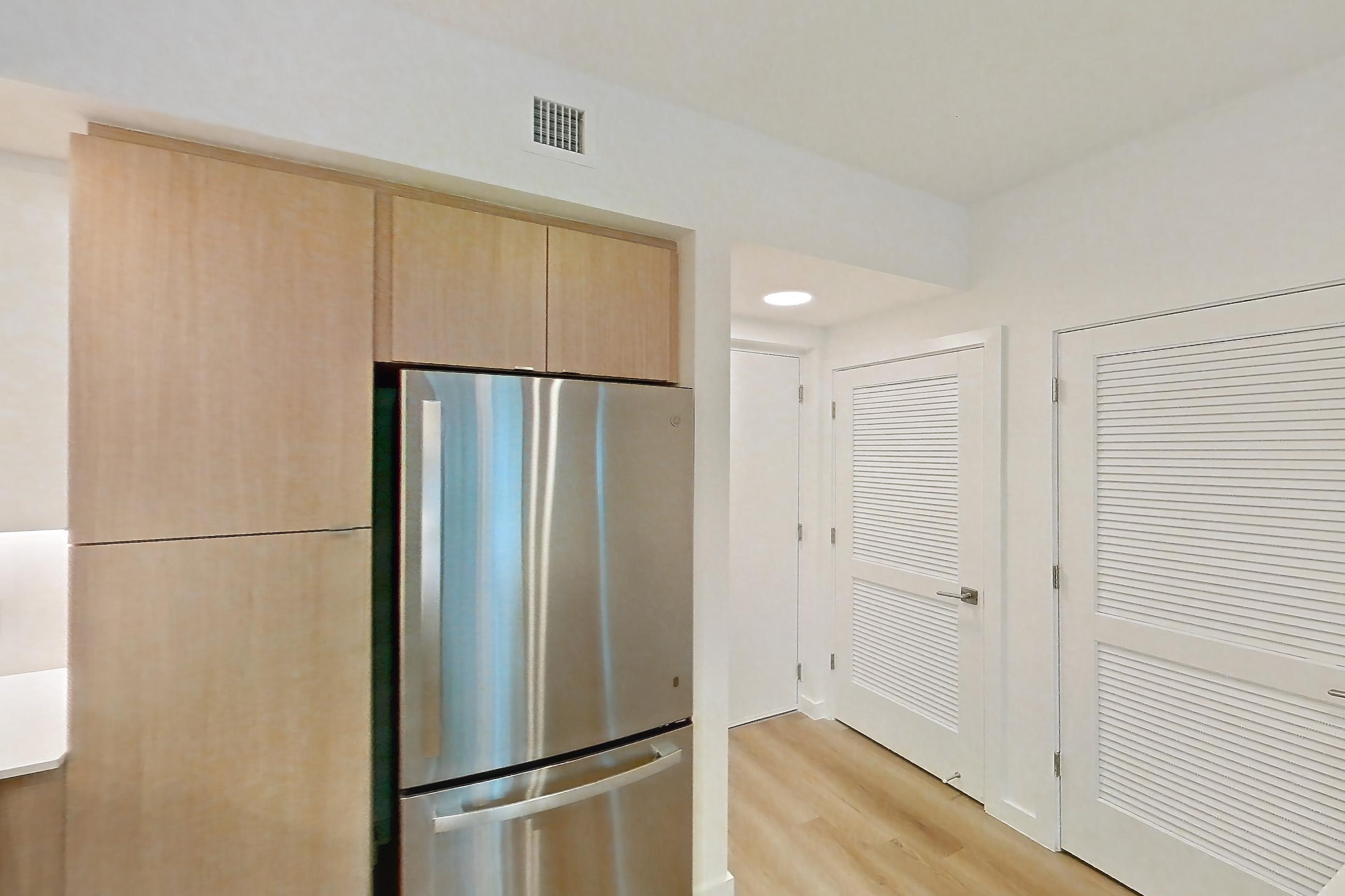 Kitchen with dishwasher, electric range, light countertops, light stone countertops, light wood-finish flooring, microwave, oven/range, refrigerator, and stainless steel appliances, Apartment 101 at Caroline Pompano Beach