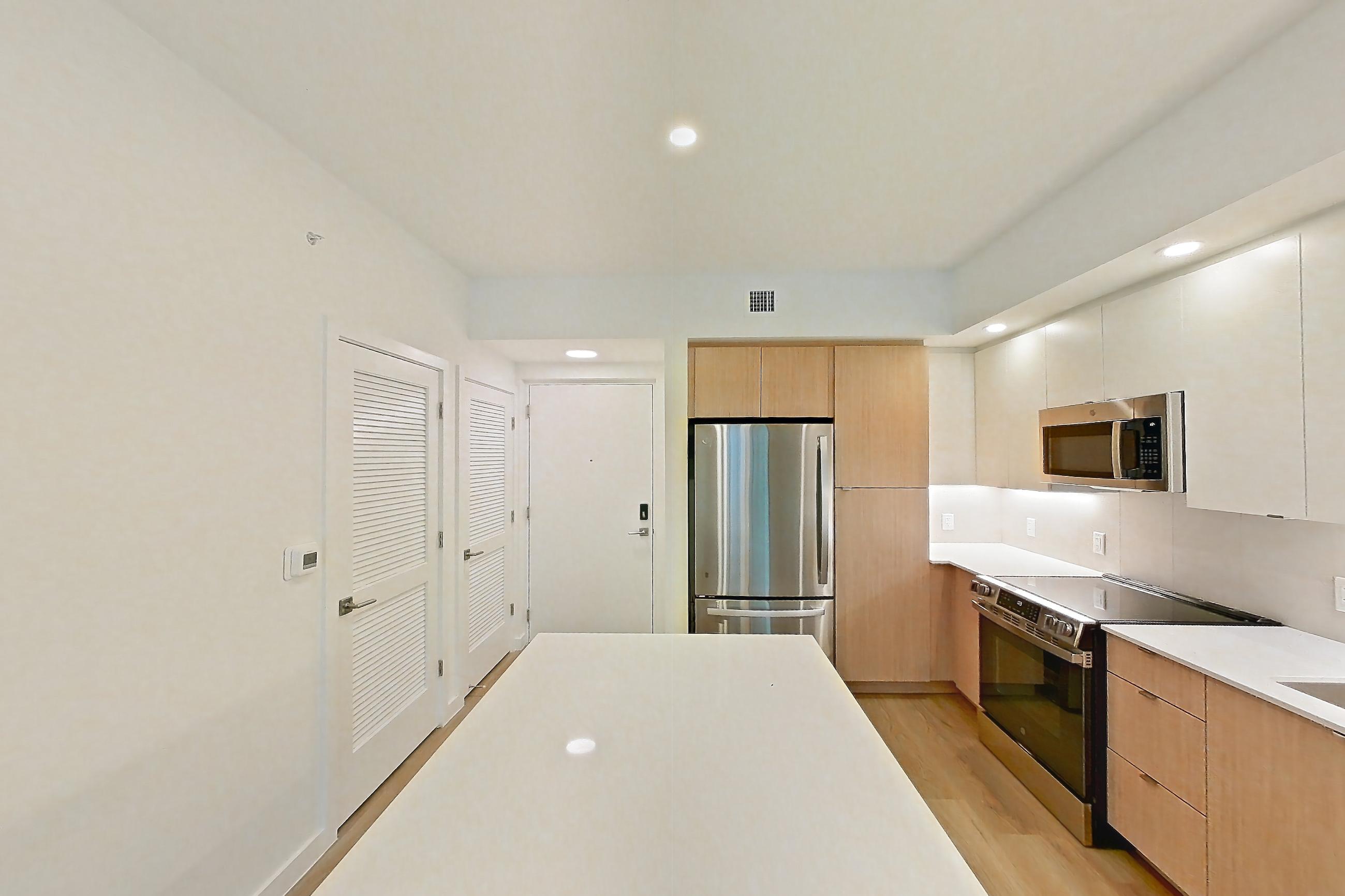 Kitchen island corner with black appliances, dishwasher, electric range, light stone countertops, light wood-finish flooring, oven/range, and stainless steel appliances, Apartment 102 at Caroline Pompano Beach