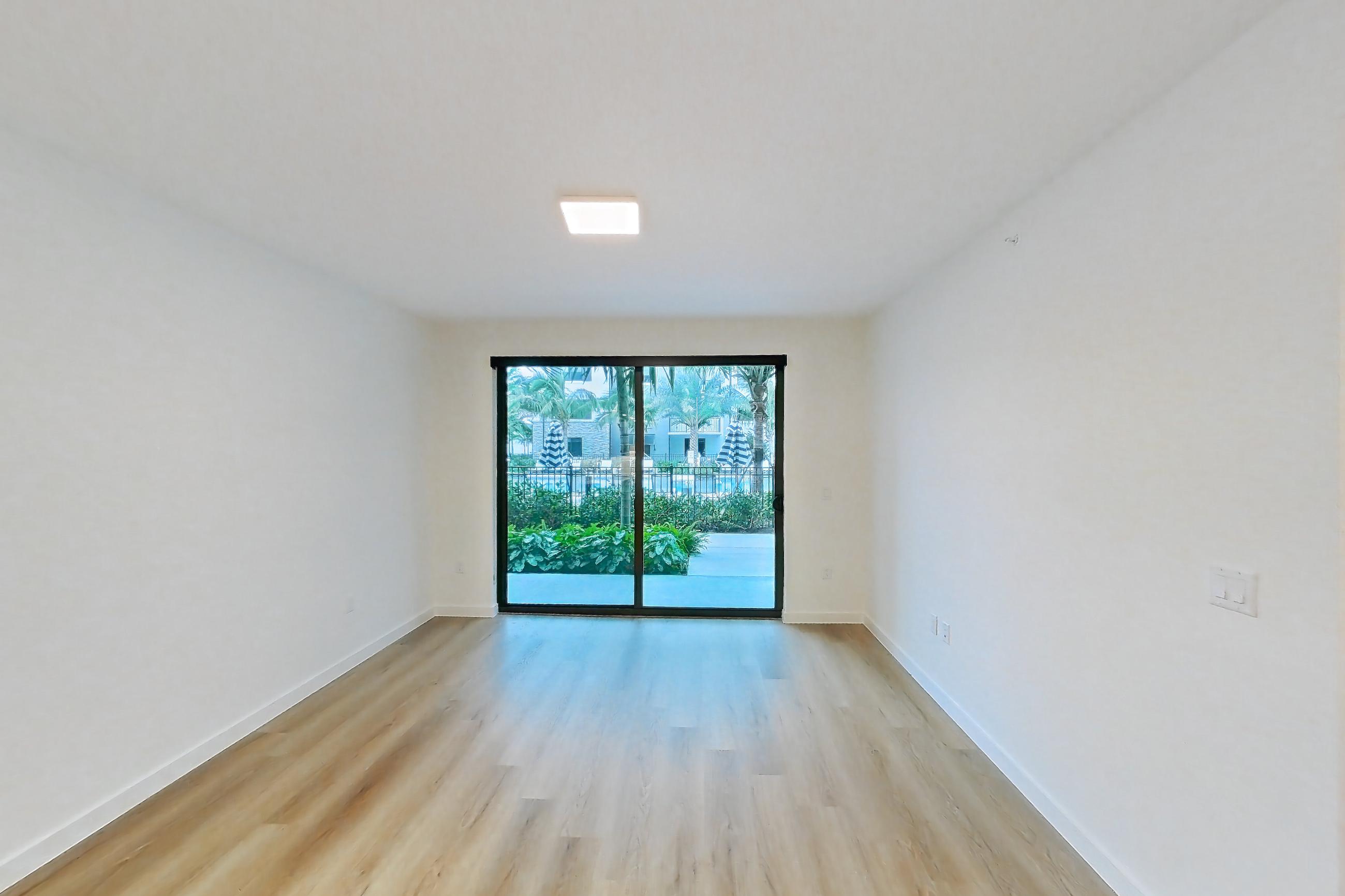 Kitchen island corner with black appliances, dishwasher, electric range, light stone countertops, light wood-finish flooring, oven/range, and stainless steel appliances, Apartment 102 at Caroline Pompano Beach