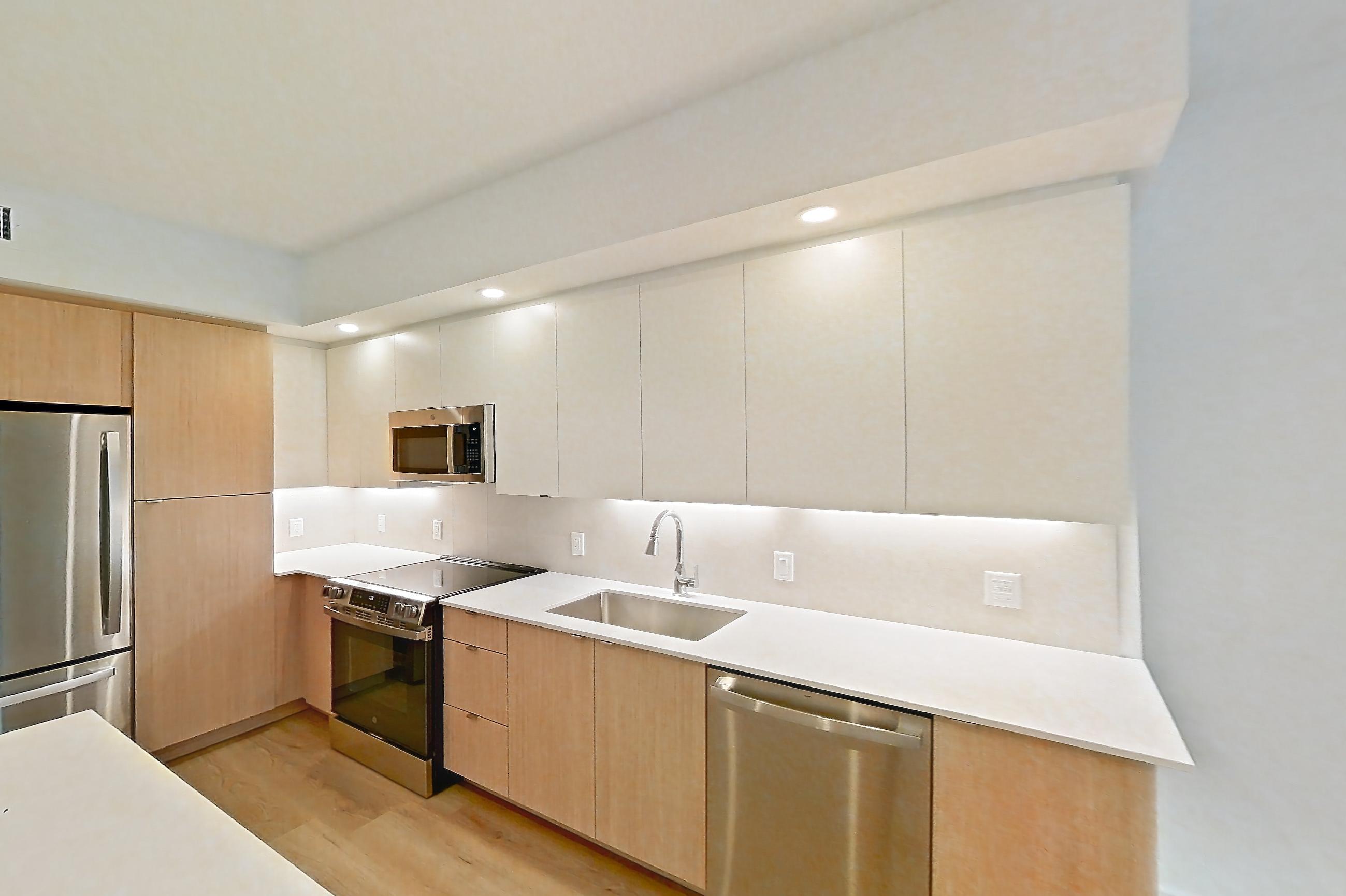 Kitchen island corner with black appliances, dishwasher, electric range, light stone countertops, light wood-finish flooring, oven/range, and stainless steel appliances, Apartment 102 at Caroline Pompano Beach