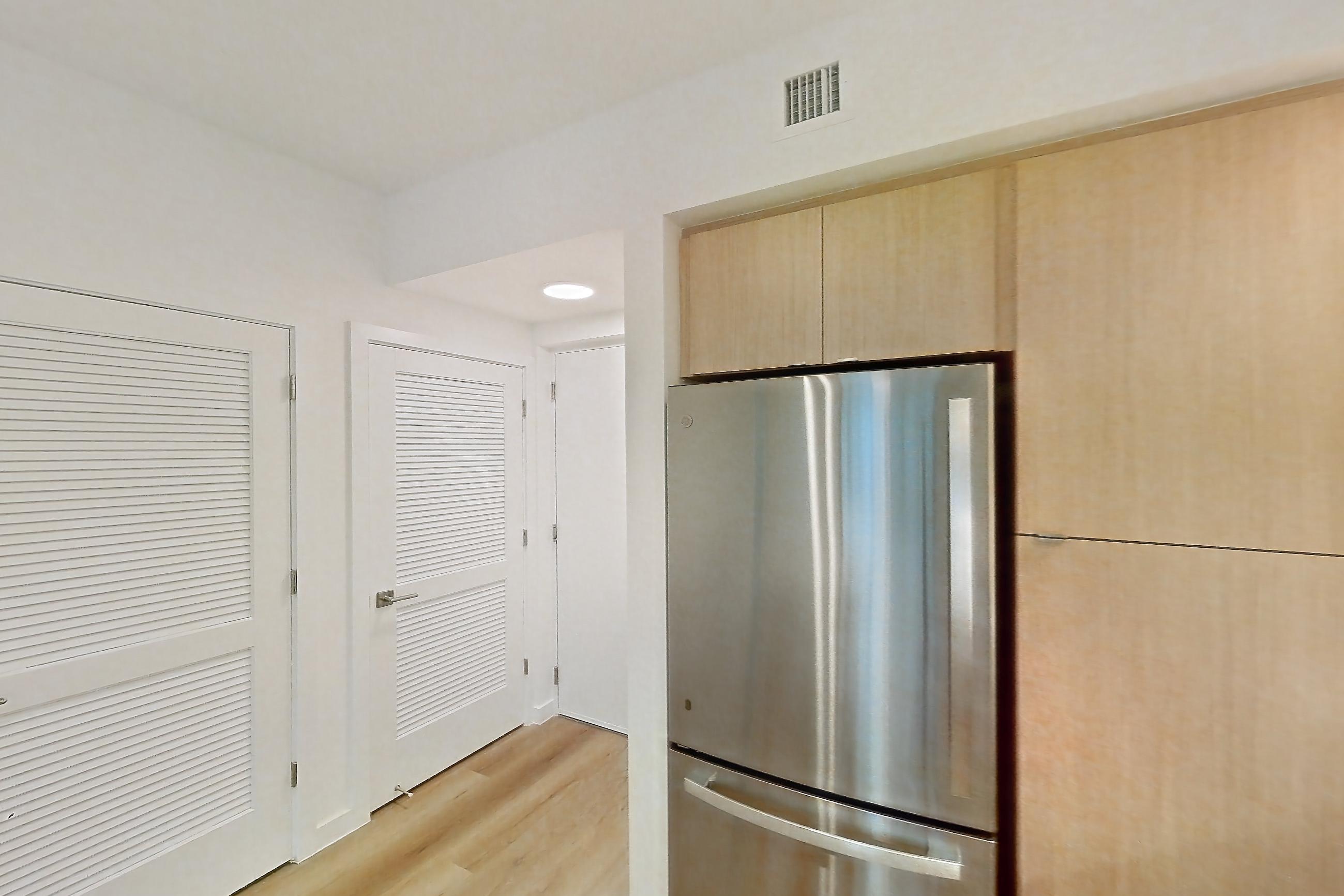 Kitchen with dishwasher, electric range, light countertops, light wood-finish flooring, microwave, oven/range, refrigerator, and stainless steel appliances, Apartment 102 at Caroline Pompano Beach