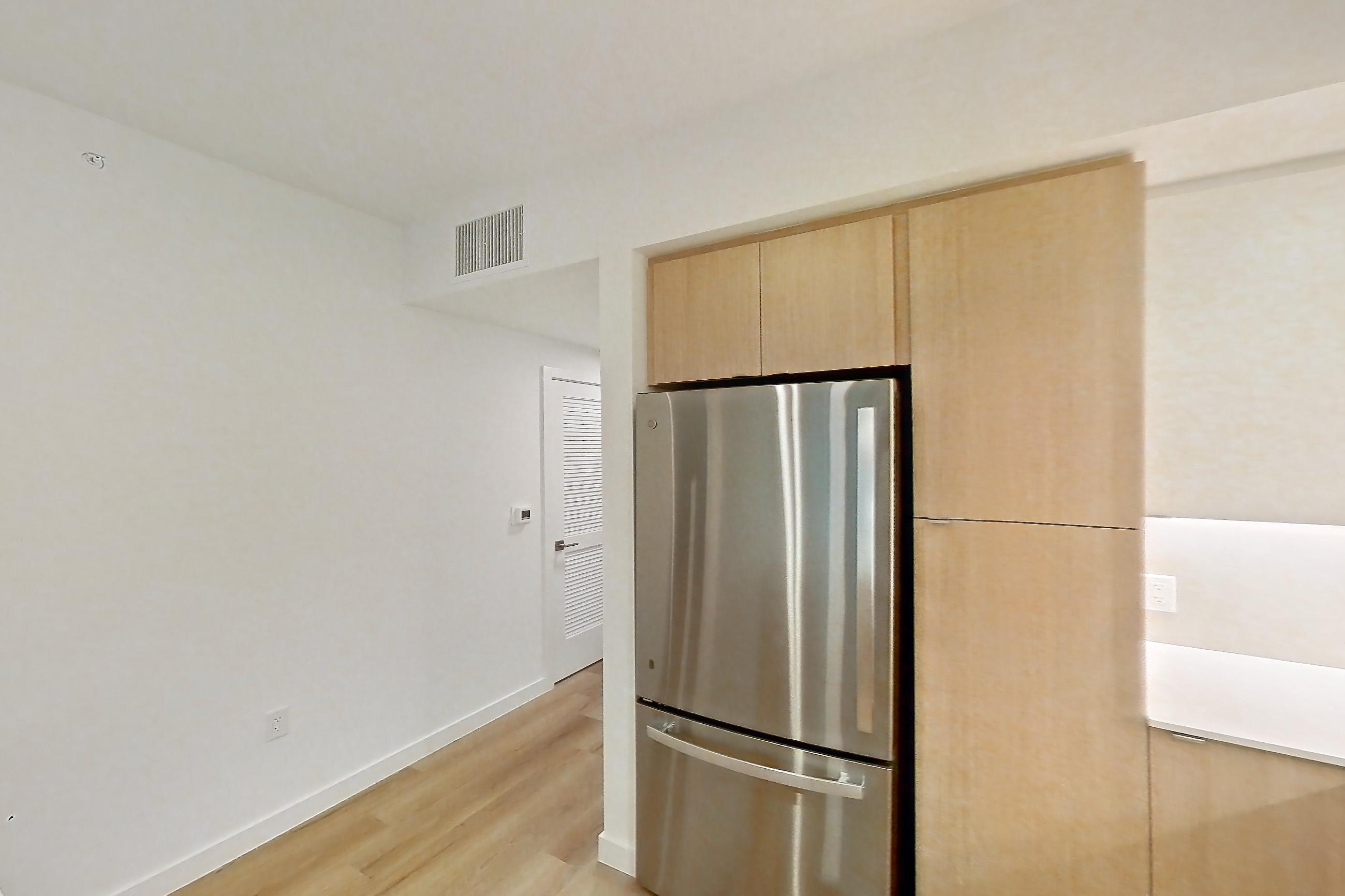 Kitchen with dishwasher, electric range, light countertops, light stone countertops, light wood-finish flooring, microwave, oven/range, refrigerator, and stainless steel appliances, Apartment 104 at Caroline Pompano Beach