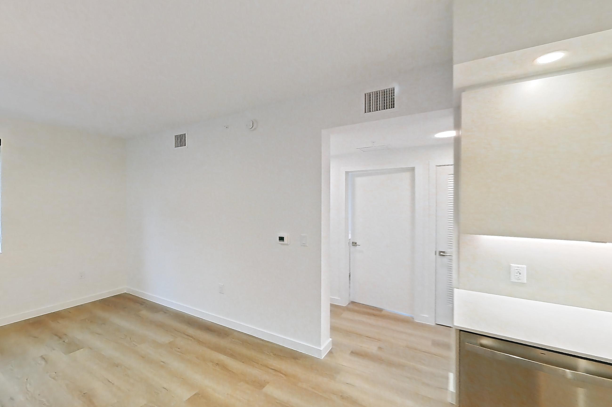 Kitchen island corner with dishwasher, light stone countertops, light wood-finish flooring, and stainless steel appliances, Apartment 106 at Caroline Pompano Beach