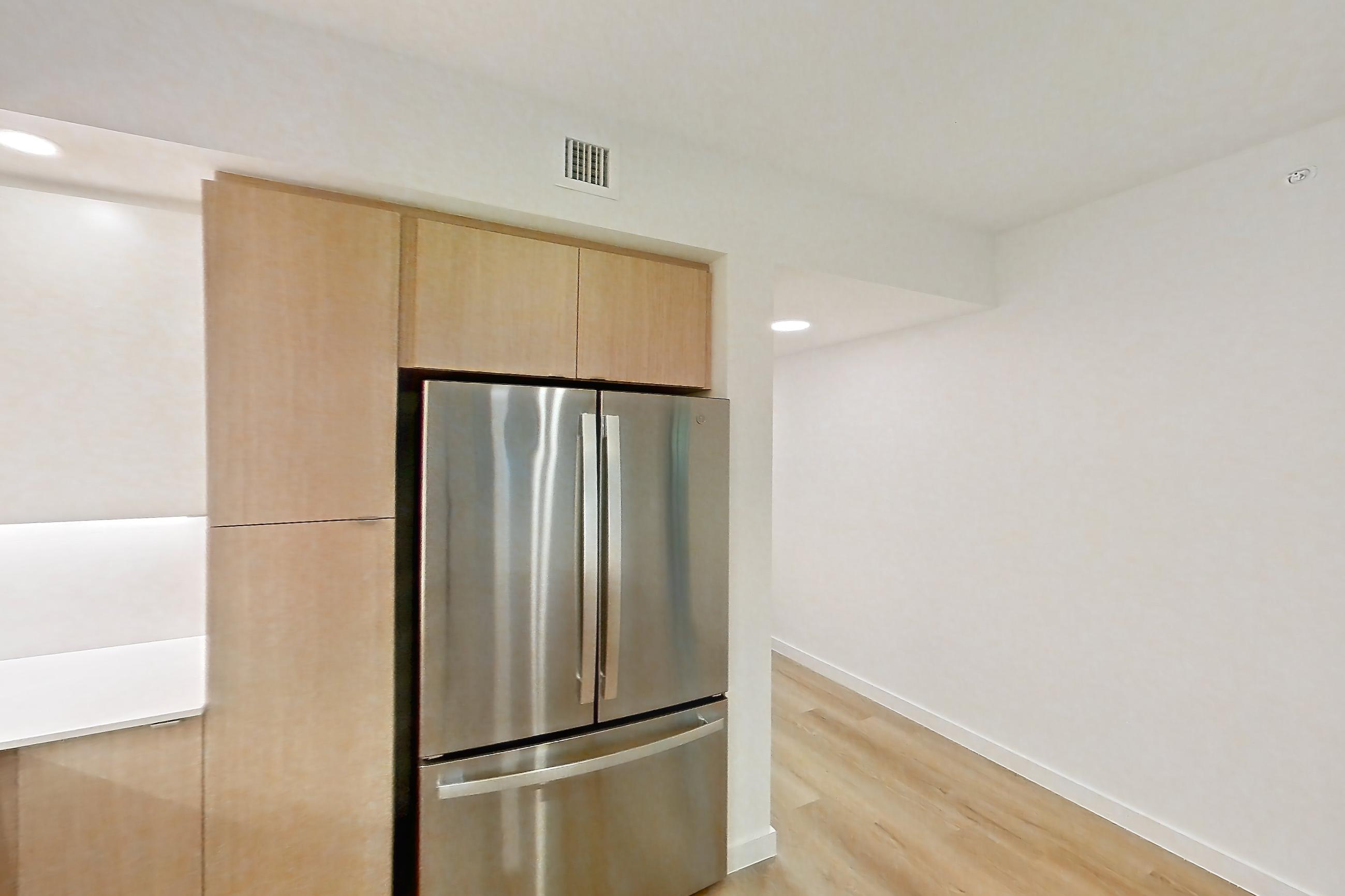 Kitchen with dishwasher, electric range, light countertops, light stone countertops, light wood-finish flooring, microwave, oven/range, refrigerator, and stainless steel appliances, Apartment 106 at Caroline Pompano Beach