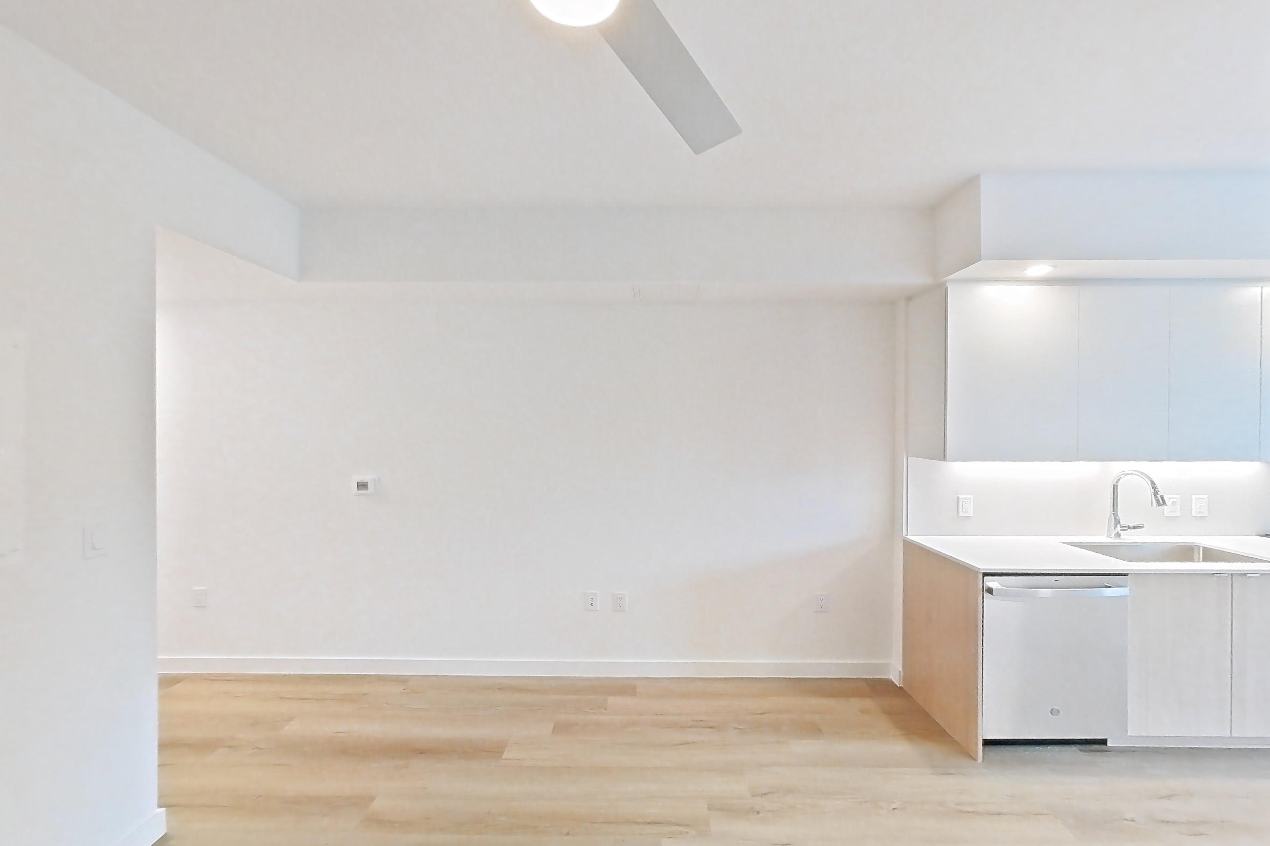 Living space with dishwasher, light wood-finish flooring, and stainless steel appliances, Apartment 109 at Caroline Pompano Beach