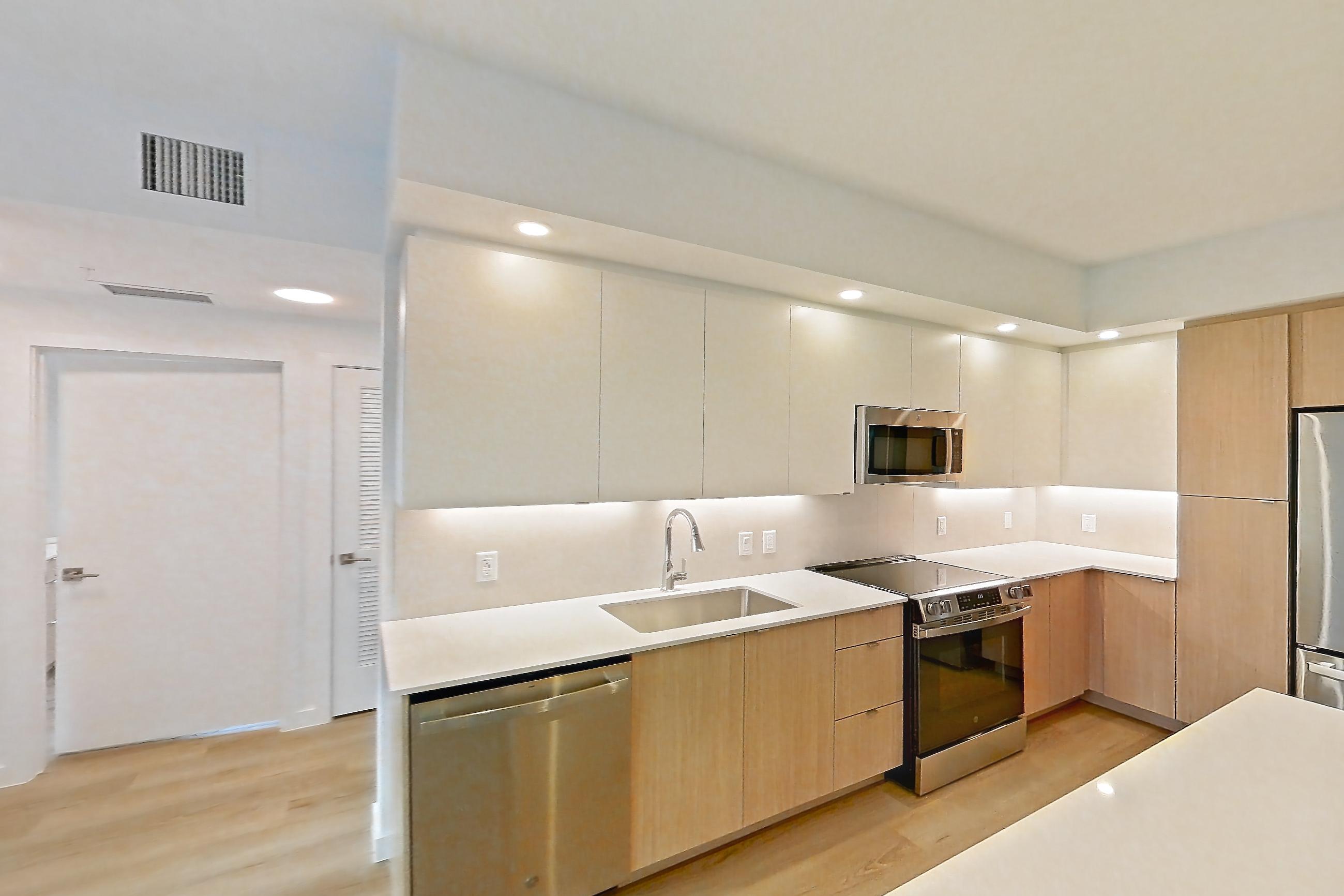 Kitchen island corner with black appliances, dishwasher, electric range, light stone countertops, light wood-finish flooring, oven/range, and stainless steel appliances, Apartment 112 at Caroline Pompano Beach