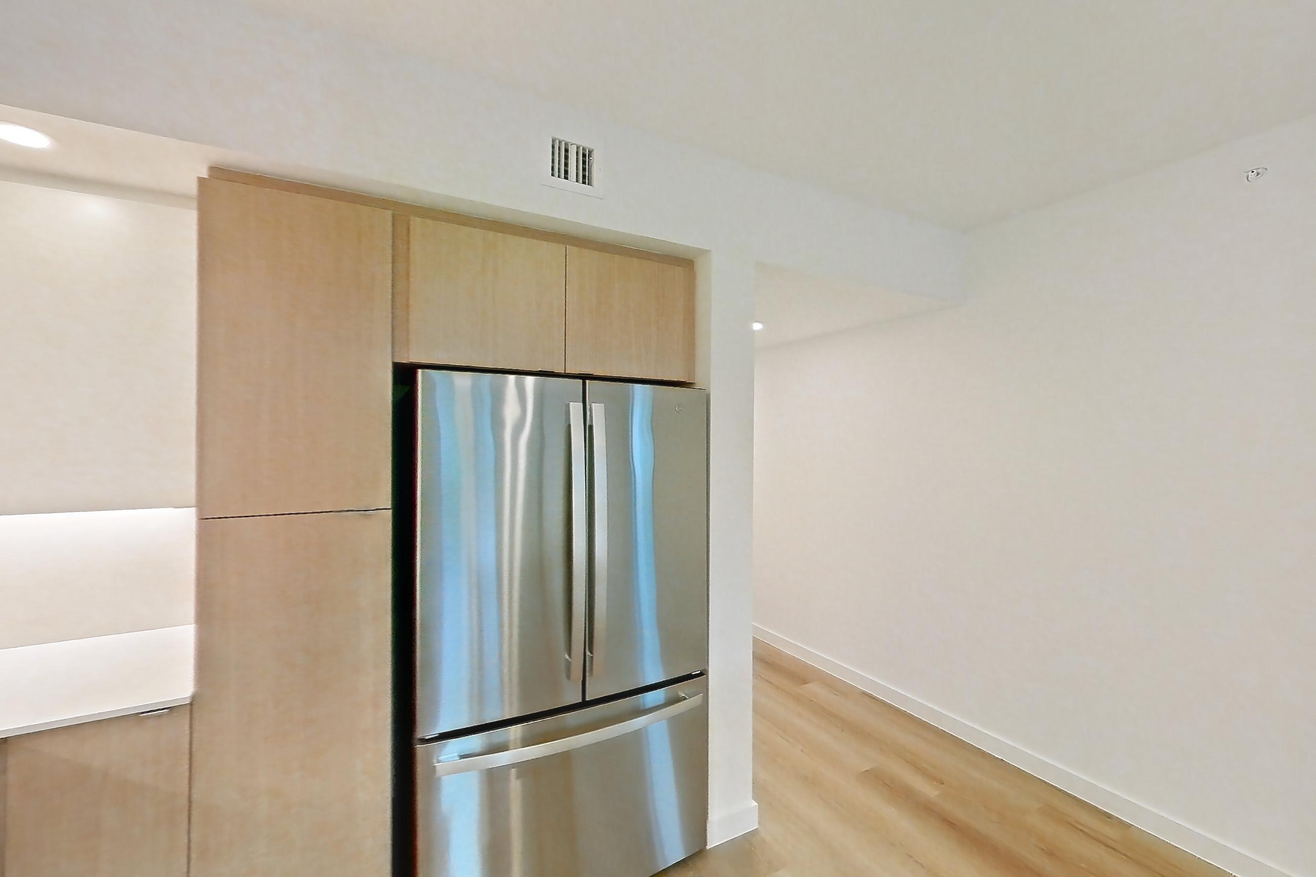 Kitchen with dishwasher, electric range, light countertops, light stone countertops, light wood-finish flooring, microwave, oven/range, refrigerator, and stainless steel appliances, Apartment 112 at Caroline Pompano Beach