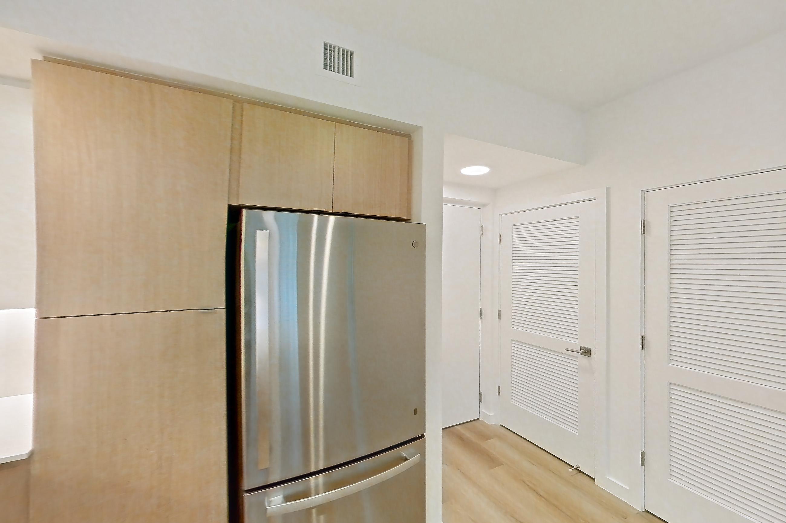 Kitchen with dishwasher, electric range, light countertops, light stone countertops, light wood-finish flooring, microwave, oven/range, refrigerator, and stainless steel appliances, Apartment 201 at Caroline Pompano Beach