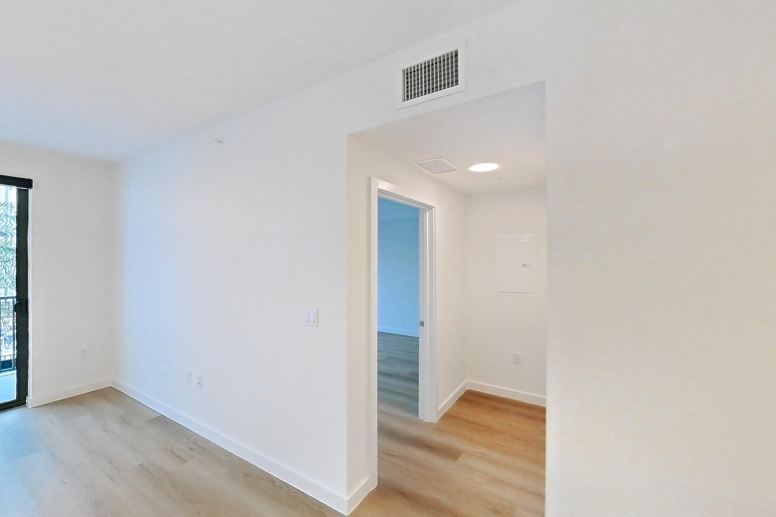 Kitchen island corner with dishwasher, light stone countertops, light wood-finish flooring, and stainless steel appliances, Apartment 205 at Caroline Pompano Beach