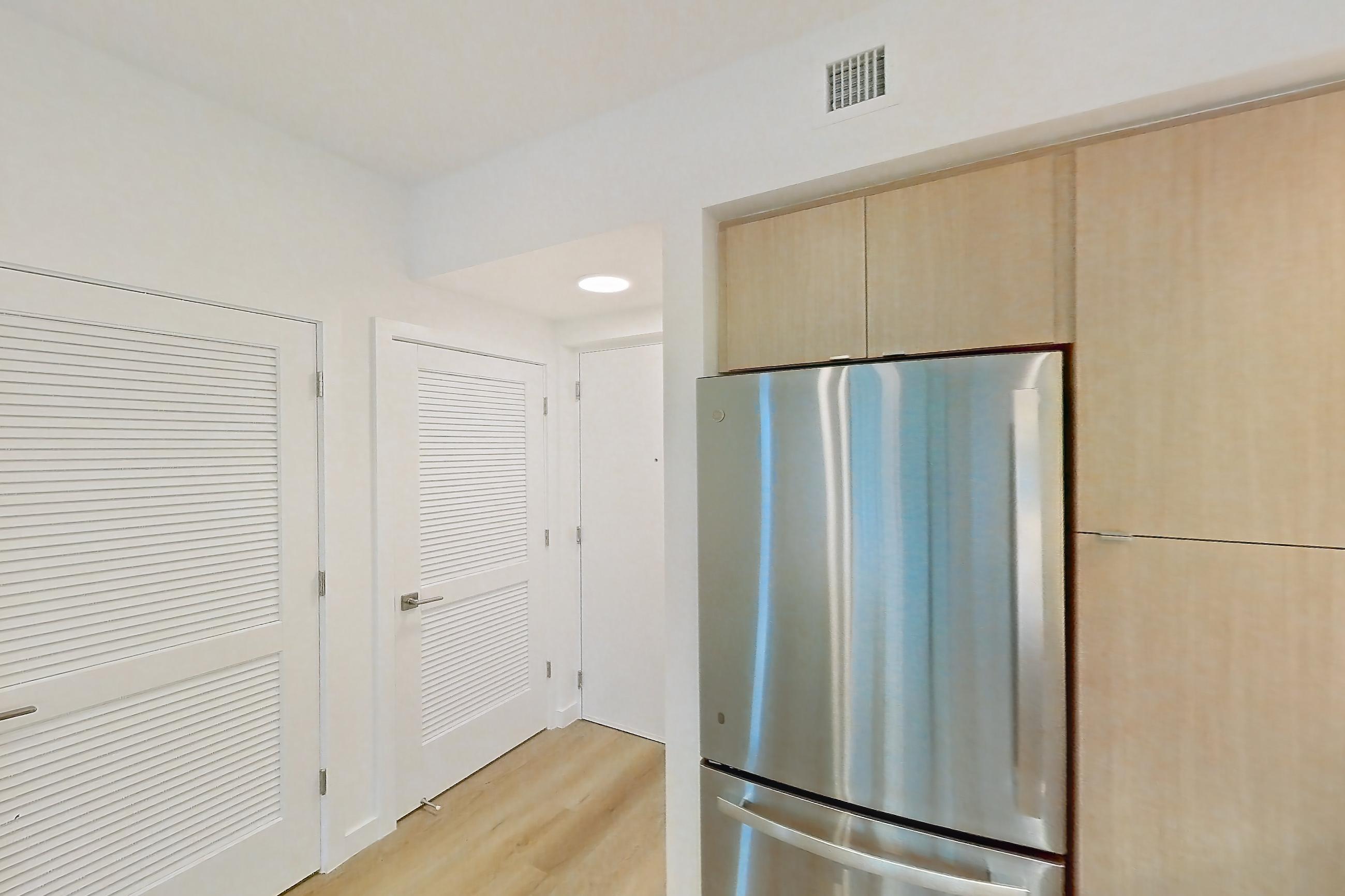 Kitchen with dishwasher, electric range, light countertops, light wood-finish flooring, microwave, oven/range, refrigerator, and stainless steel appliances, Apartment 205 at Caroline Pompano Beach