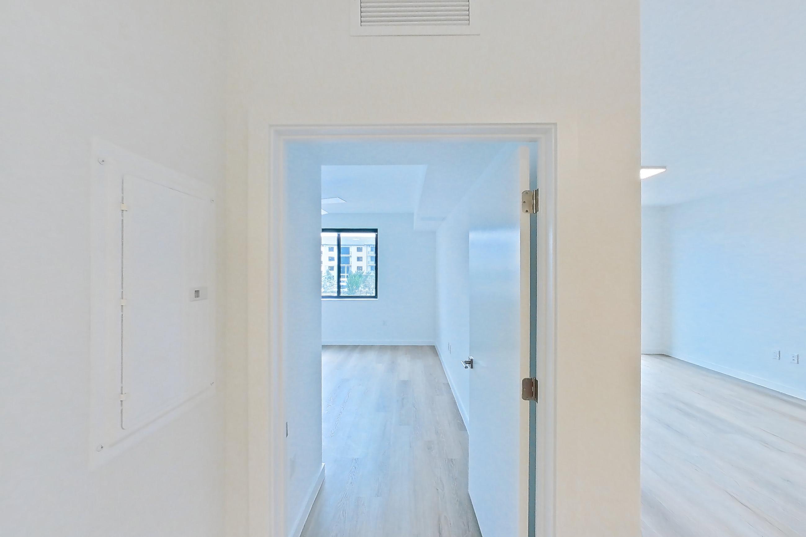 Kitchen island corner with black appliances, electric range, light countertops, light wood-finish flooring, oven/range, refrigerator, and stainless steel appliances, Apartment 208 at Caroline Pompano Beach